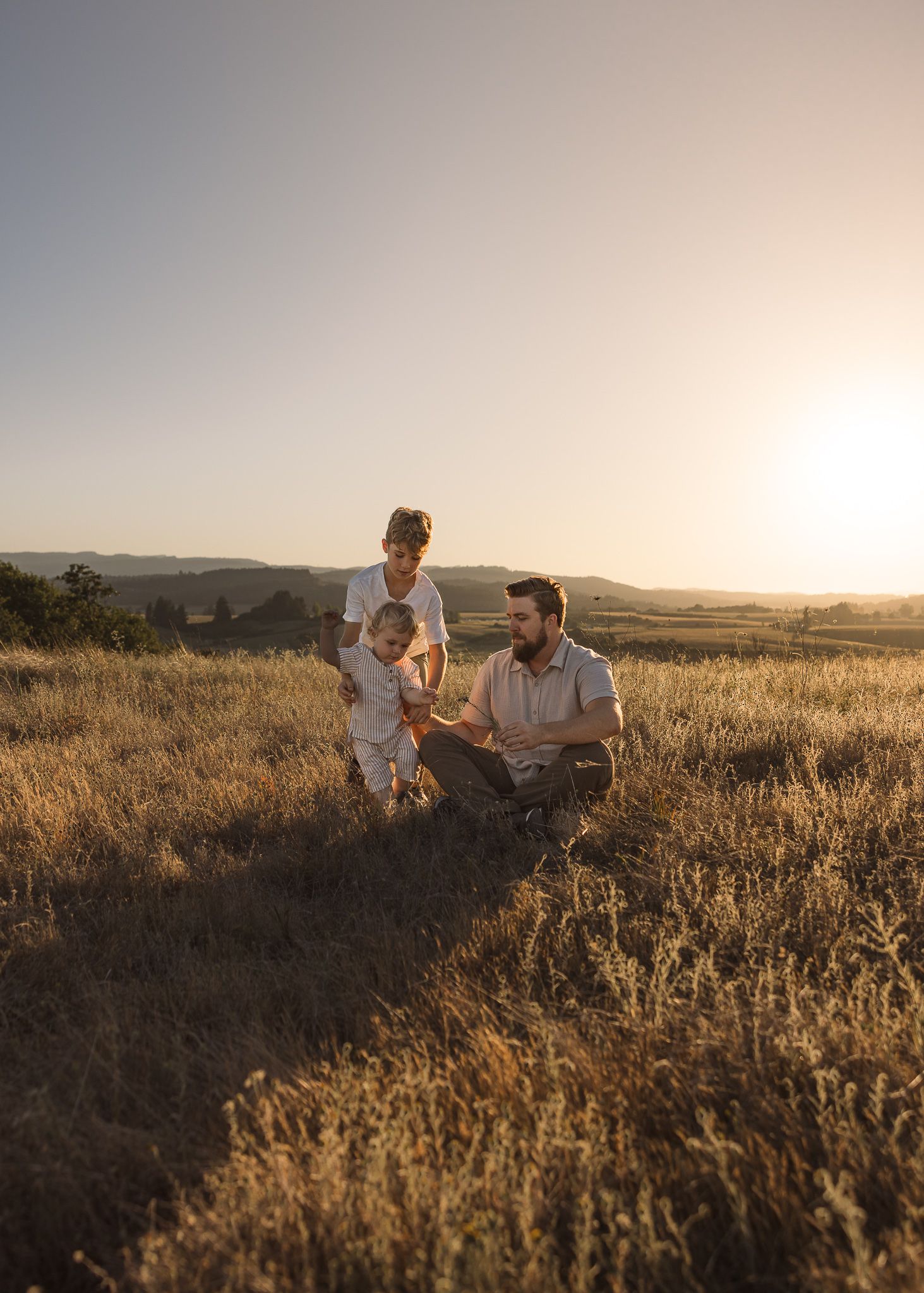 Family enjoying sunset together in a golden field during golden hour during a photo session by Salem, Oregon family photographer