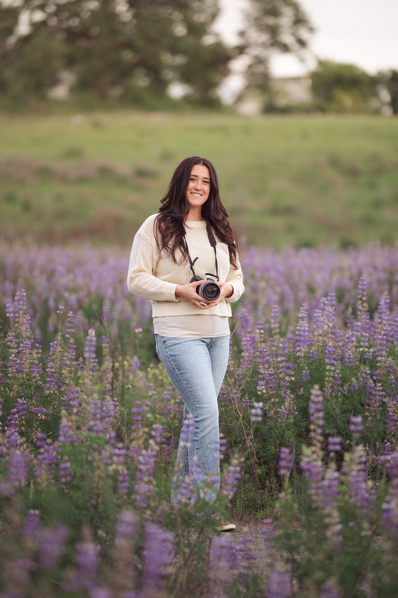 Salem, Oregon family and senior photographer Hannah Walter smiling while taking photos in a blooming field of purple lupines.