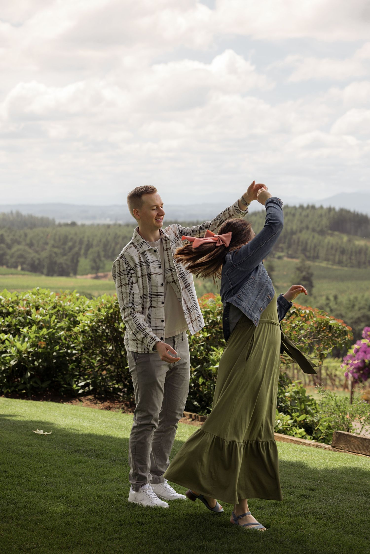 A joyful celebration moment at a scenic winery overlooking green hills and valleys.