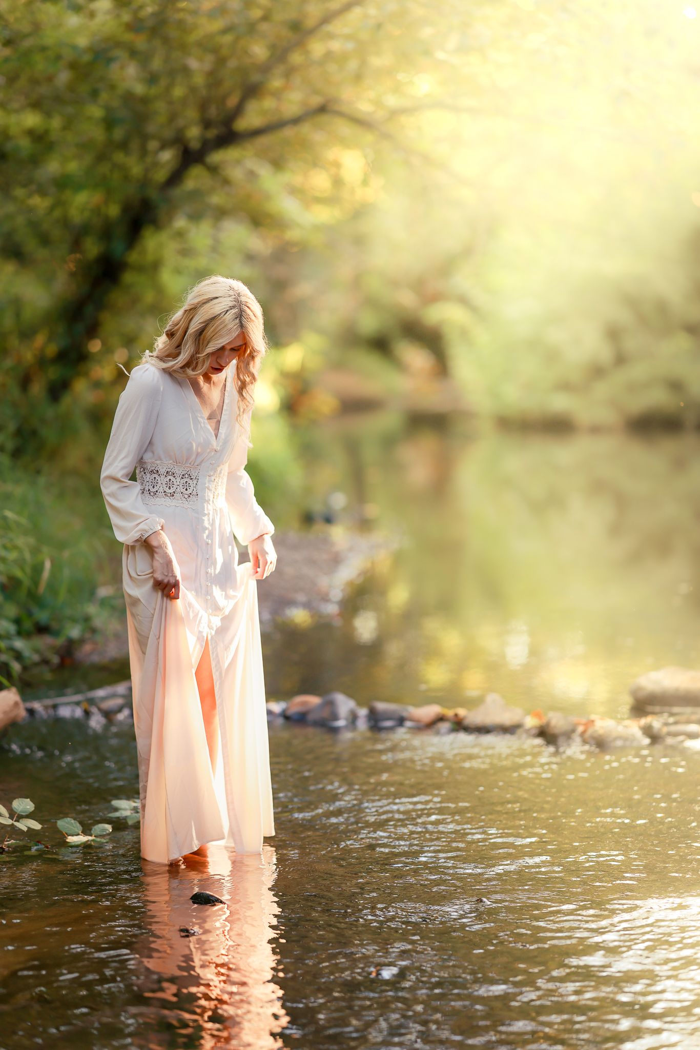 Woman in white dress standing in shallow water during golden hour during a photo session taken by Salem, Oregon senior photographer.