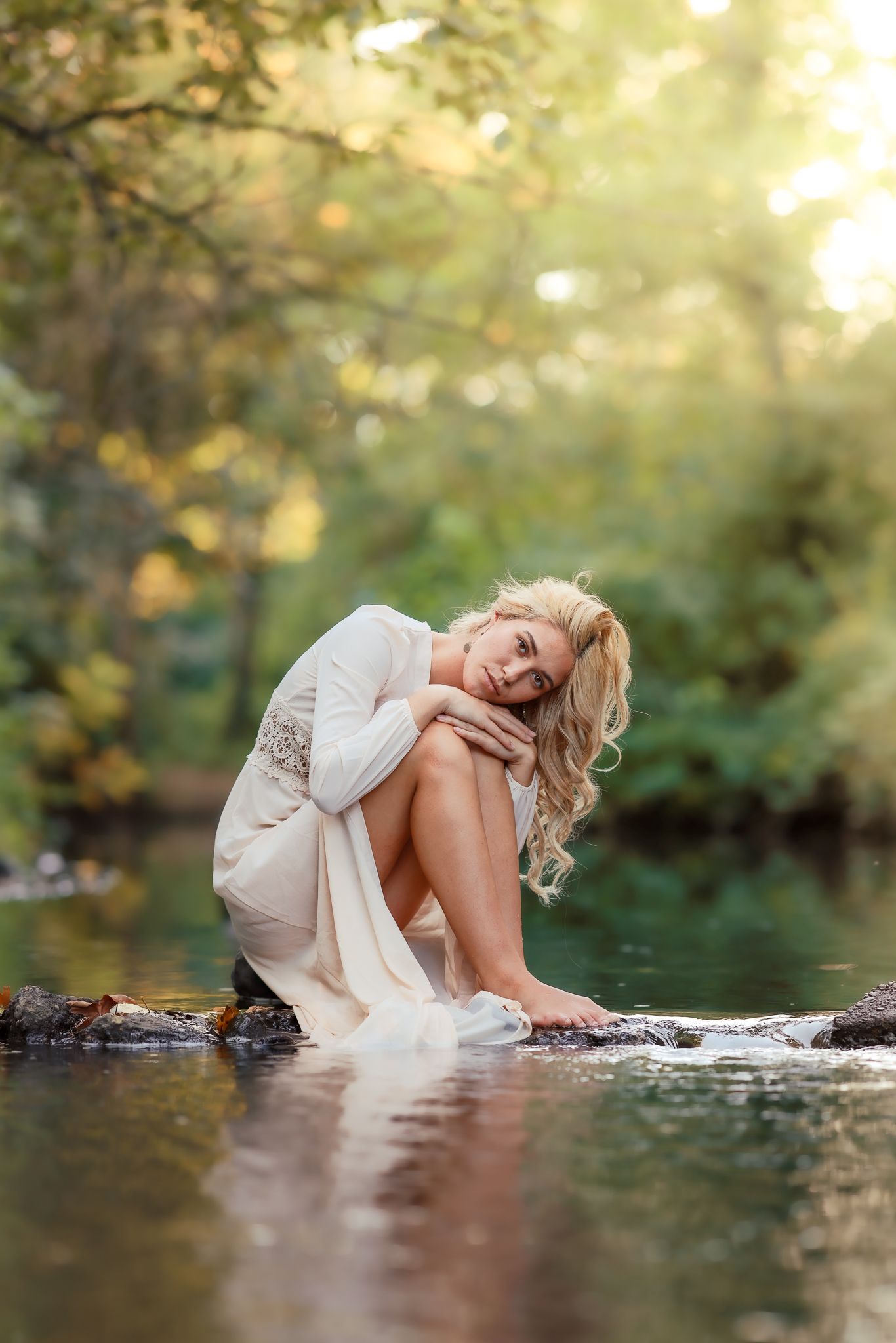 Senior posed artistically on rocks in a stream with ethereal lighting during a photo session taken by Salem, Oregon senior photographer.