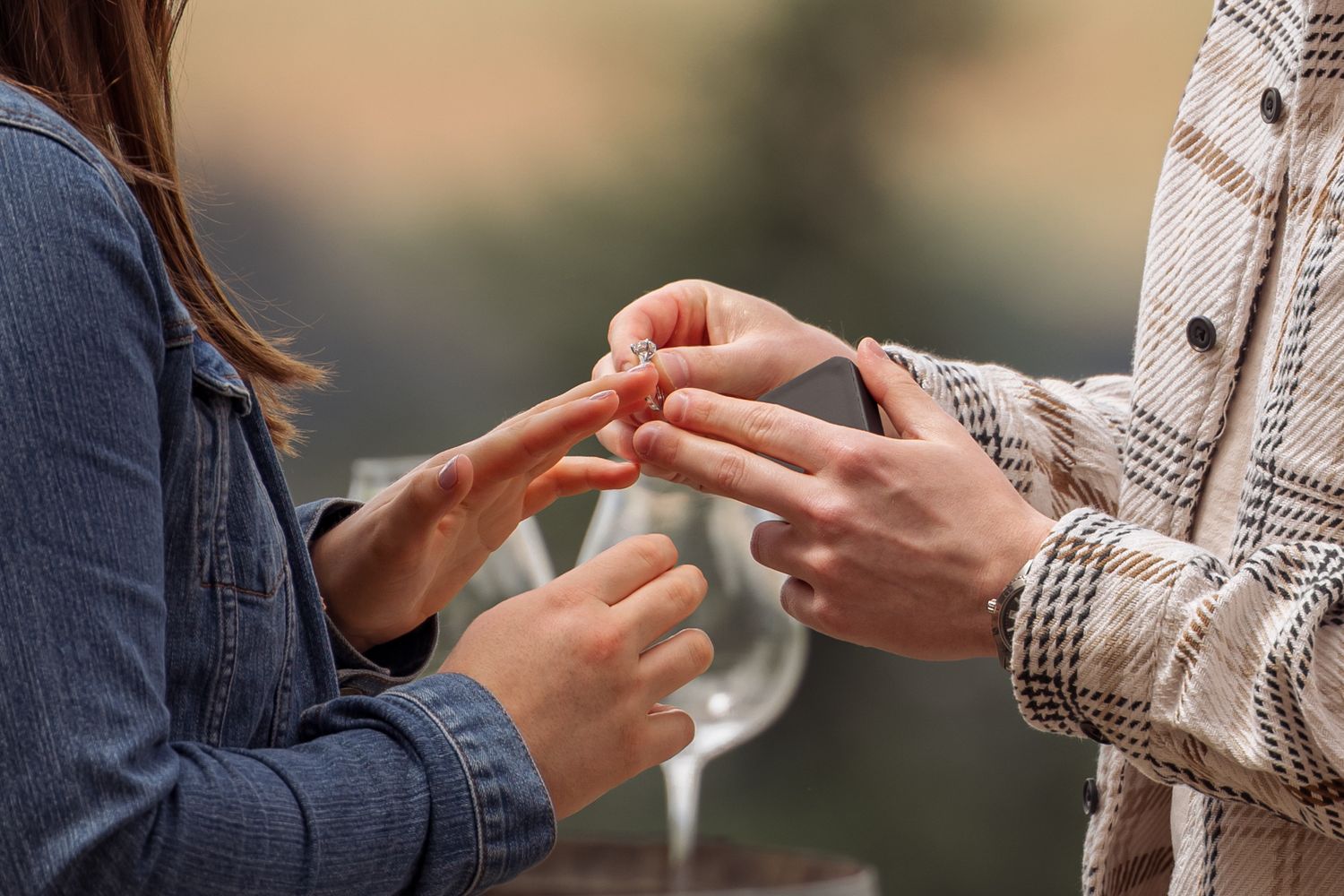 Two hands exchanging a phone against a blurred background shows mobile device sharing between people.