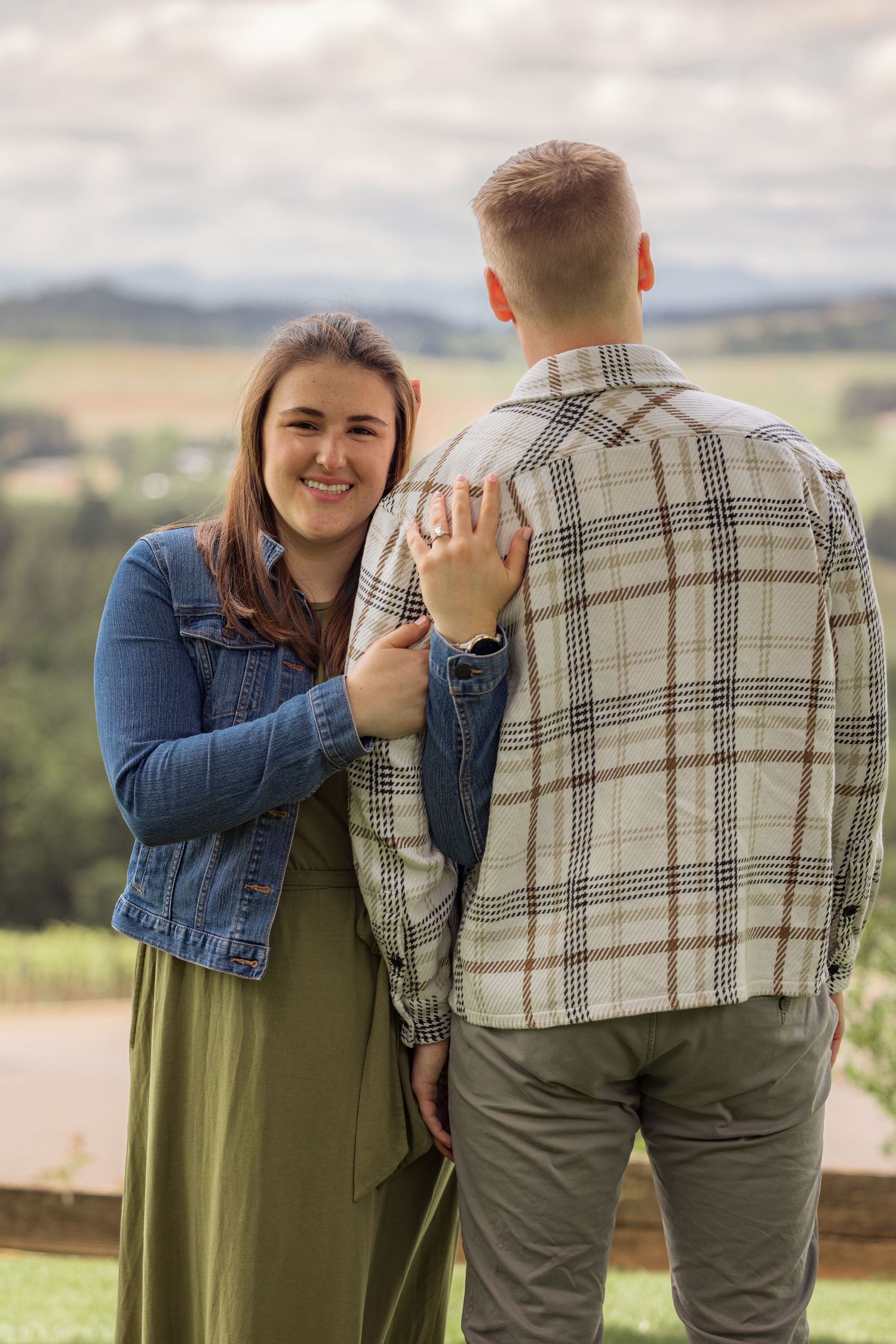 A joyful embrace at a scenic winery overlook with rolling hills in the background.