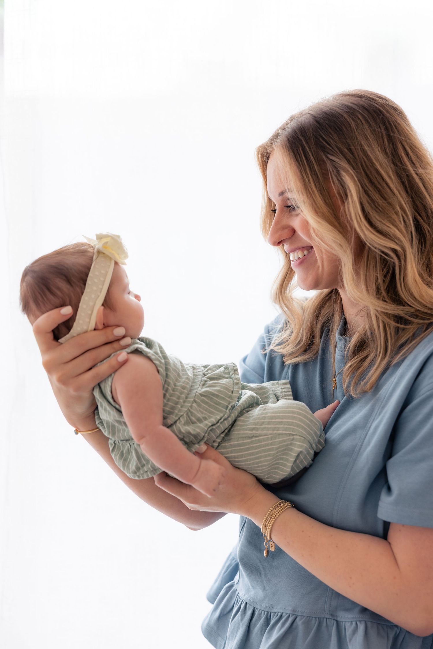 A series of four progressive images showing someone cradling and lifting a small baby in blue dress.