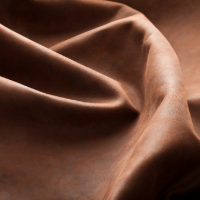 Smooth brown silk fabric creates elegant waves and folds in a sepia-toned close-up photograph.