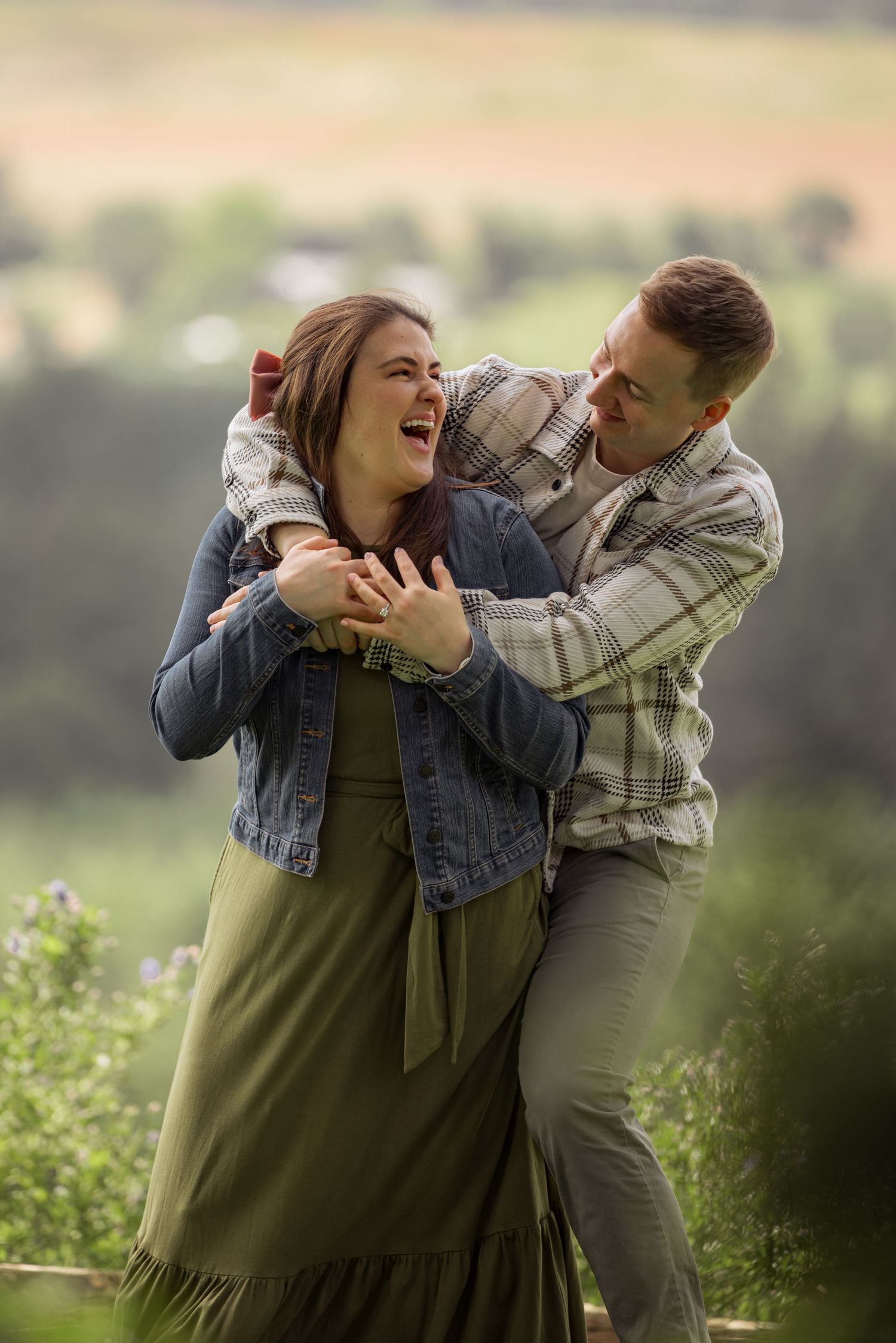 A joyful couple sharing an intimate moment and laughing together in a scenic outdoor setting.