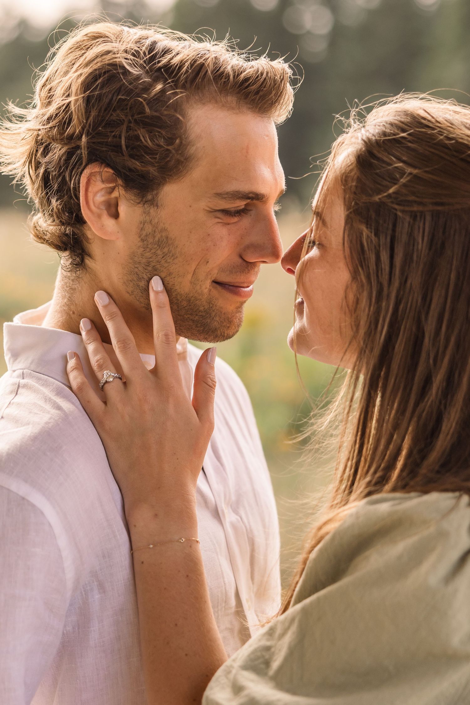 A romantic couple shares tender moments in a series of intimate outdoor portraits at sunset with soft bokeh lighting.