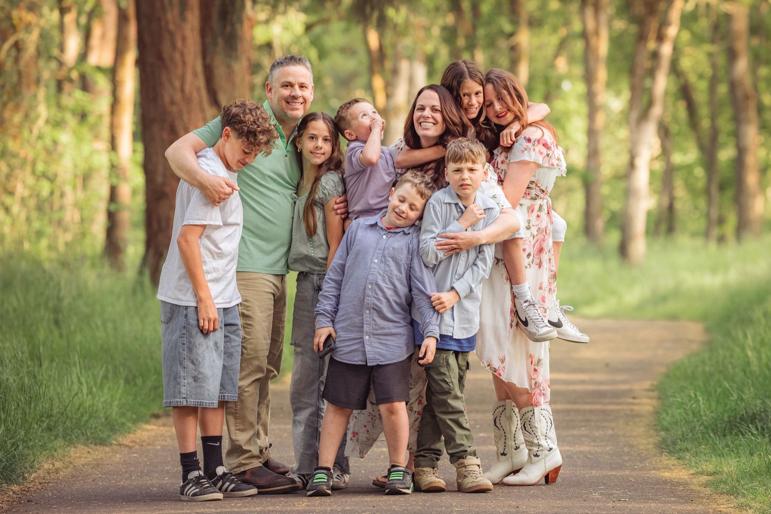 A cheerful extended family walking together on a tree-lined path during a photo session taken by Salem, Oregon family photographer.