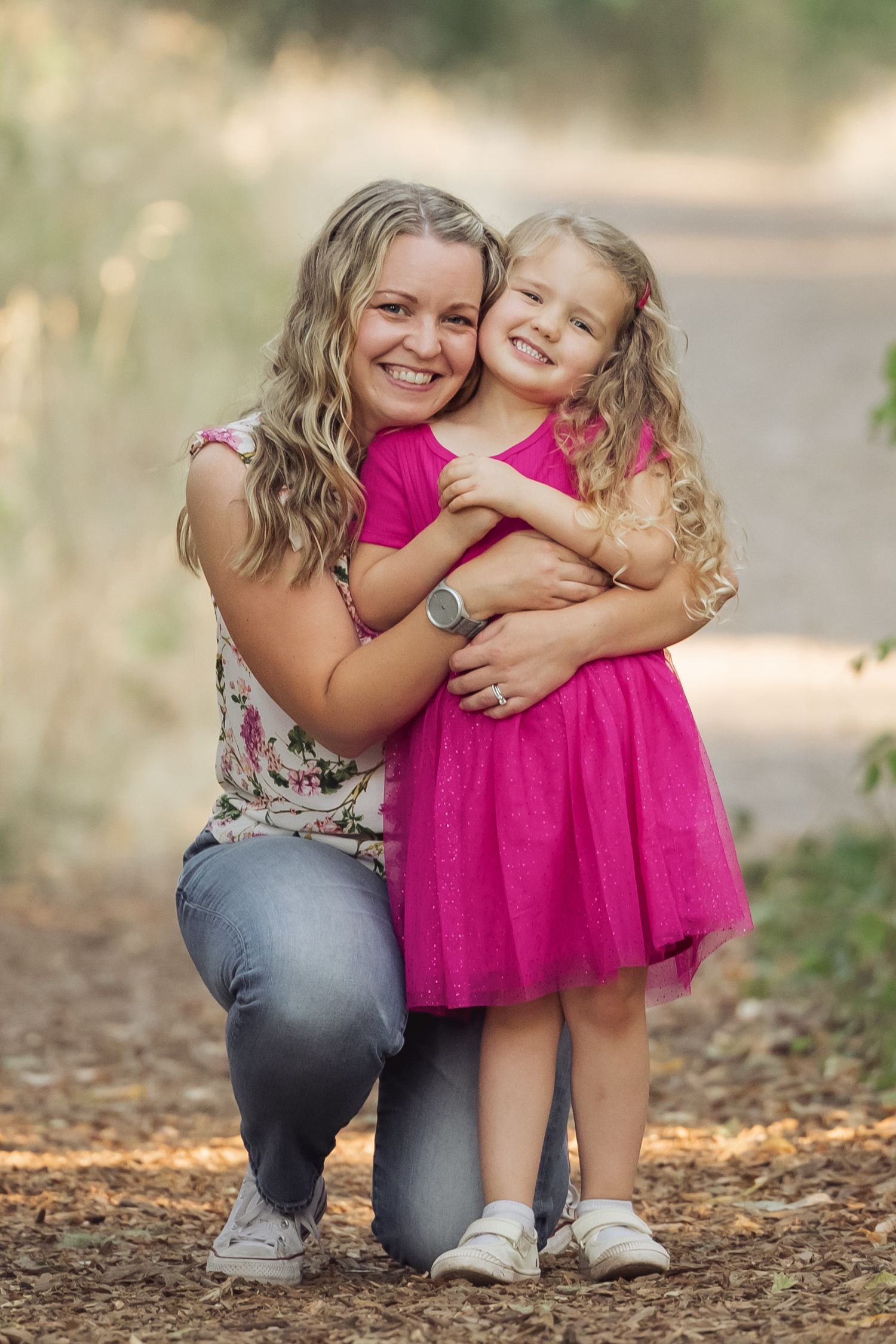 A parent and child share a tender moment outdoors while wearing coordinating pink and denim outfits.