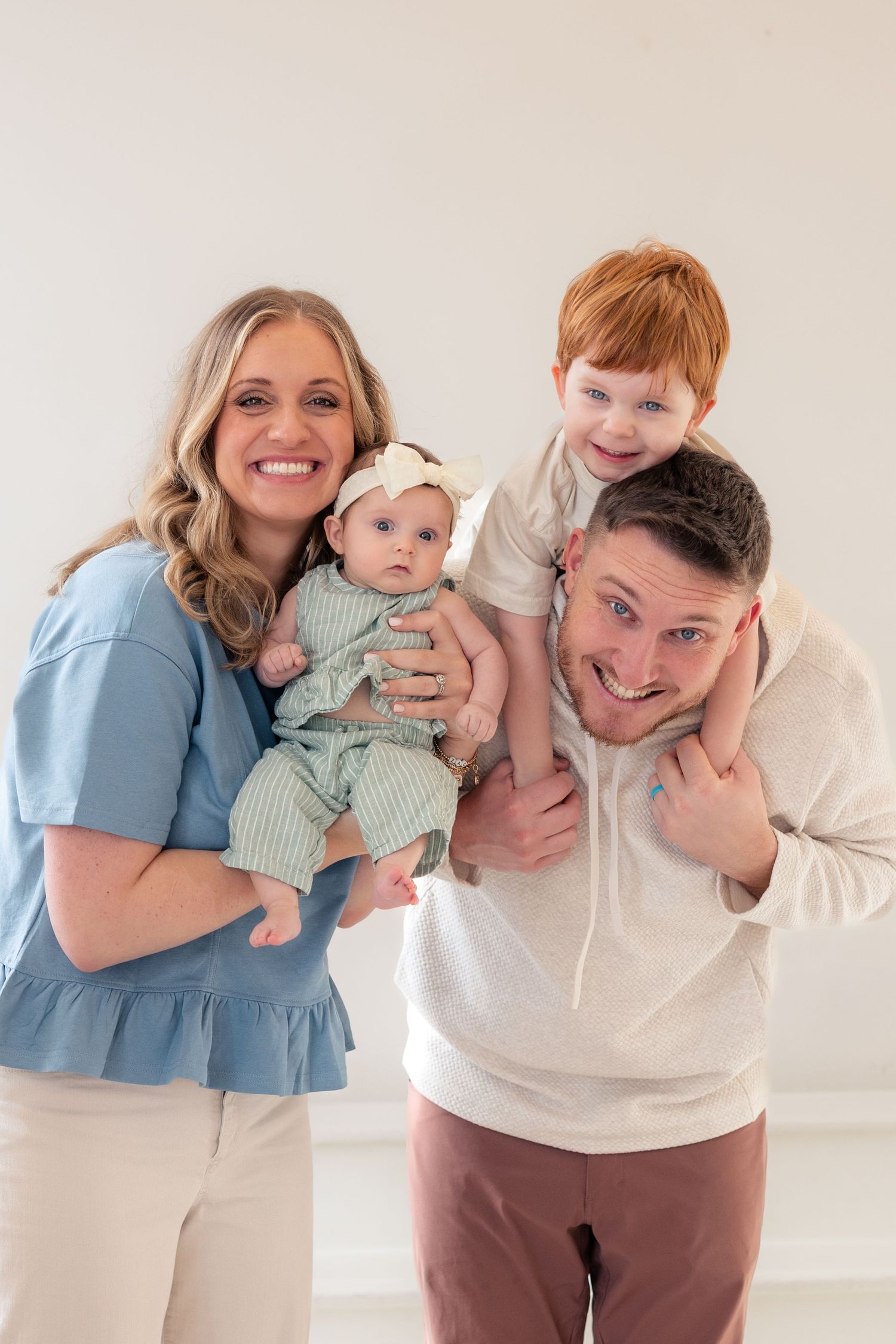 A smiling family of four poses together for a studio photography session in Salem, Oregon. Salem, Oregon family photographer.
