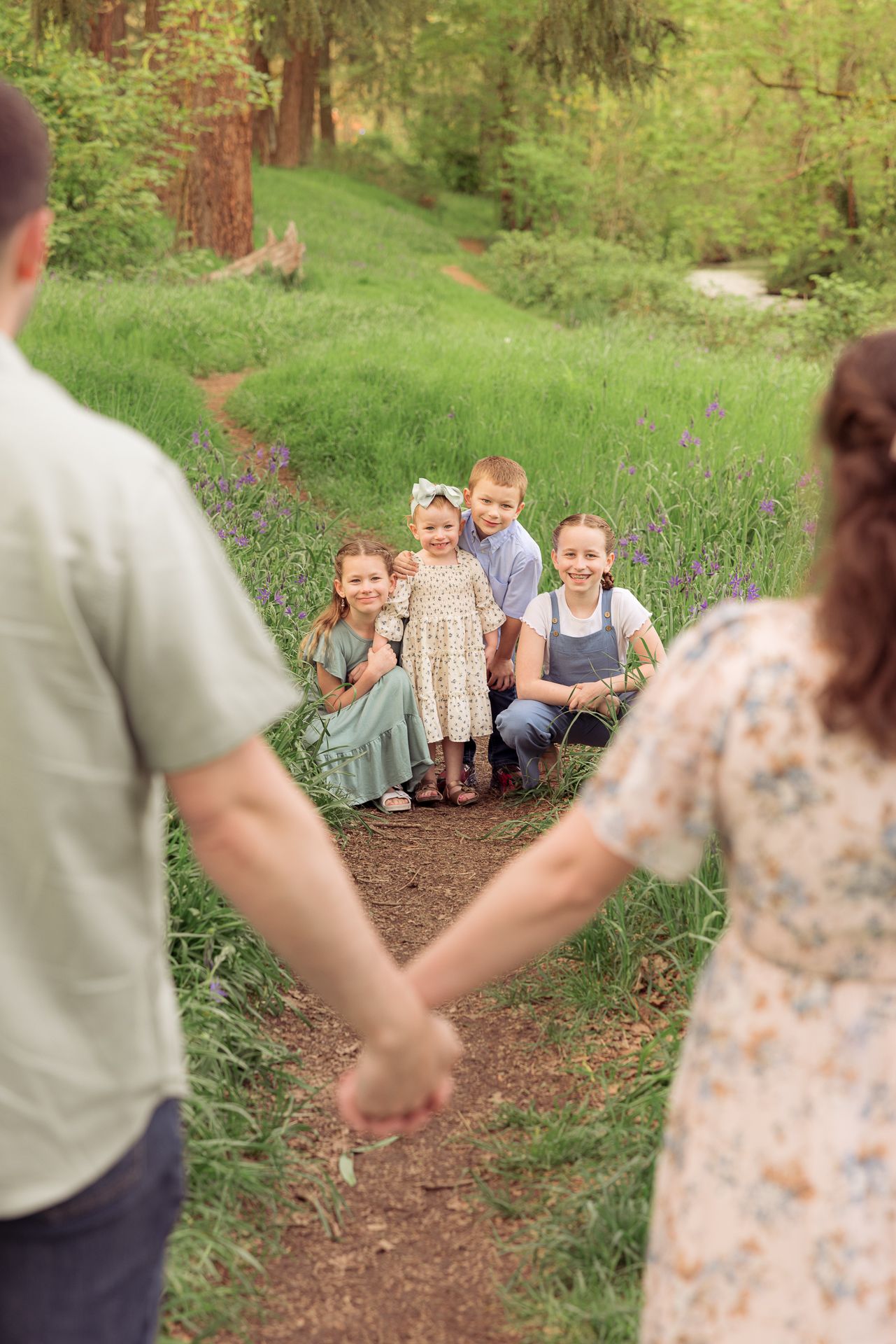 Happy family walking together on a dirt trail surrounded by lush greenery taken by Salem, Oregon family photographer.