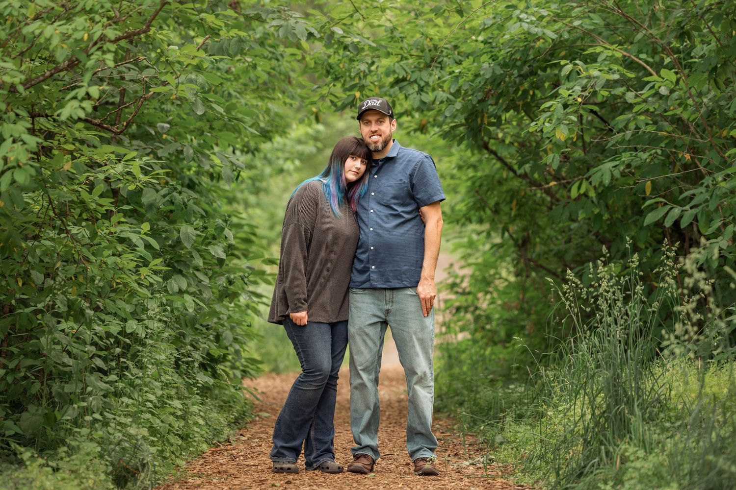 People walking together on a green wooded path surrounded by lush vegetation and trees.