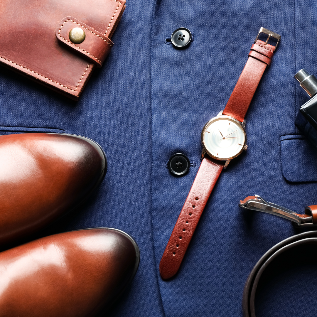 A collection of brown leather accessories including watch straps and wallets arranged on dark blue fabric background.