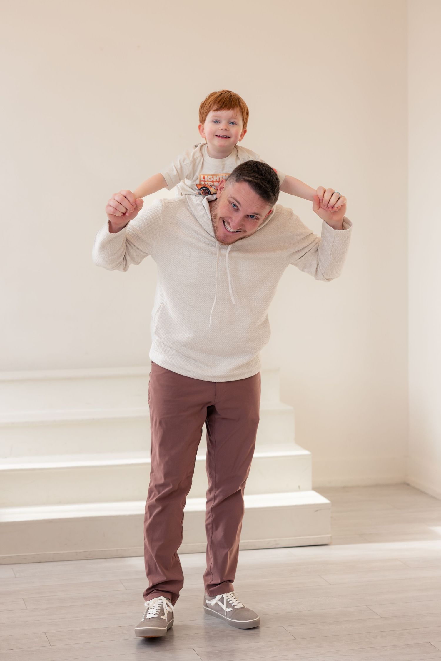 Person in a white sweater and brown pants strikes playful poses against a light-colored wall in a sequence of photos.