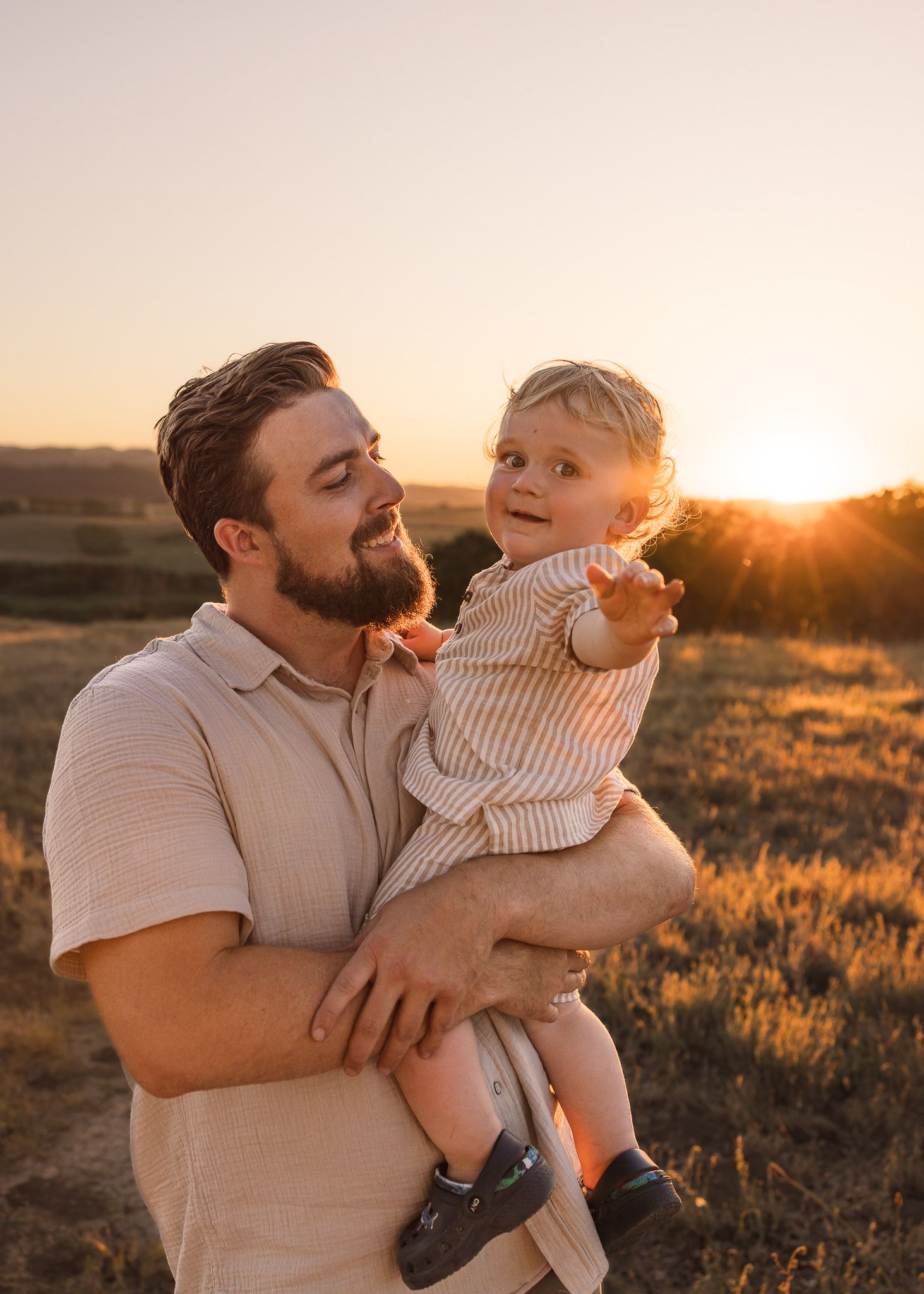 Tender father and child moments captured at sunset in a field.