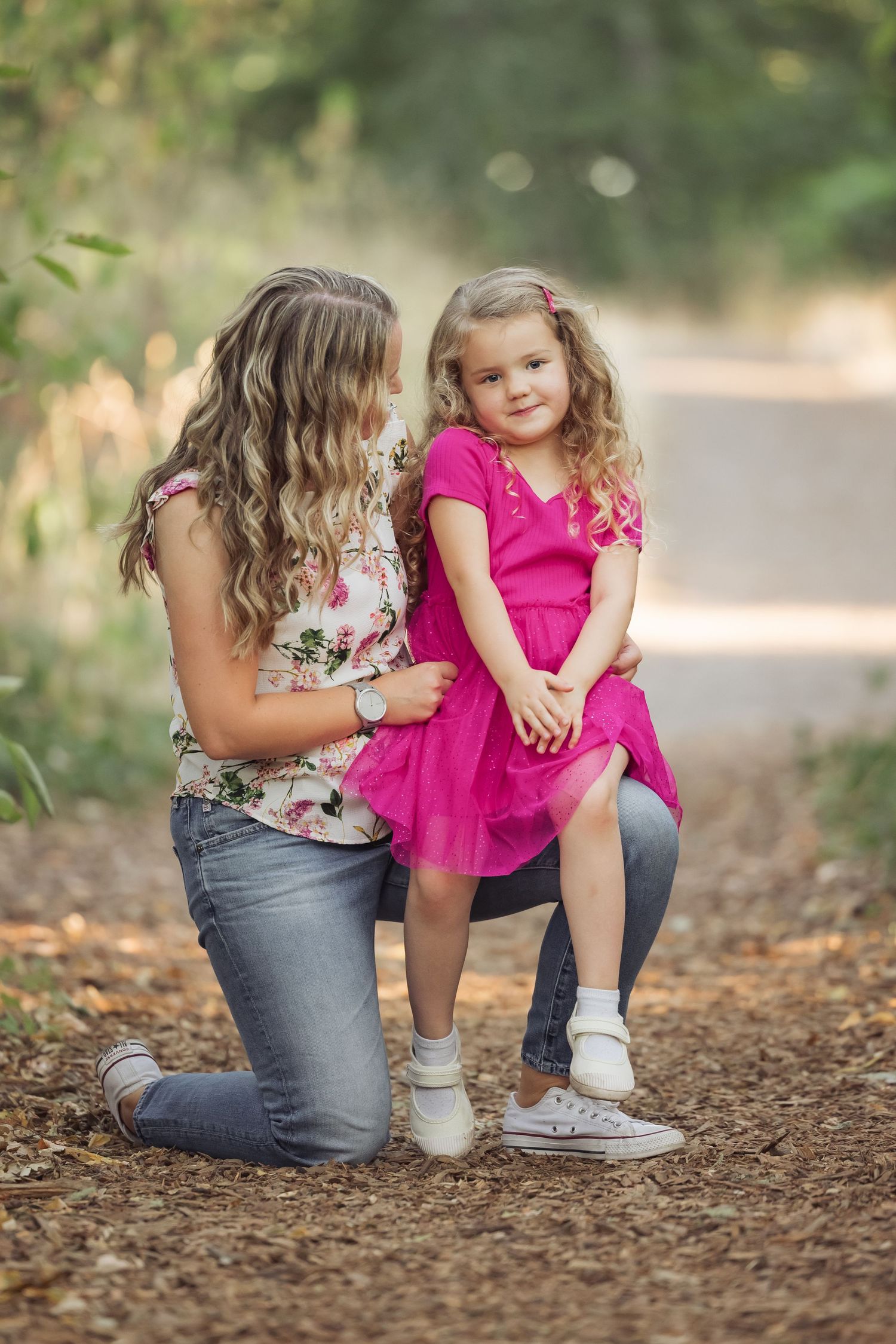 A tender moment between parent and child on a dirt path surrounded by soft bokeh and natural light.