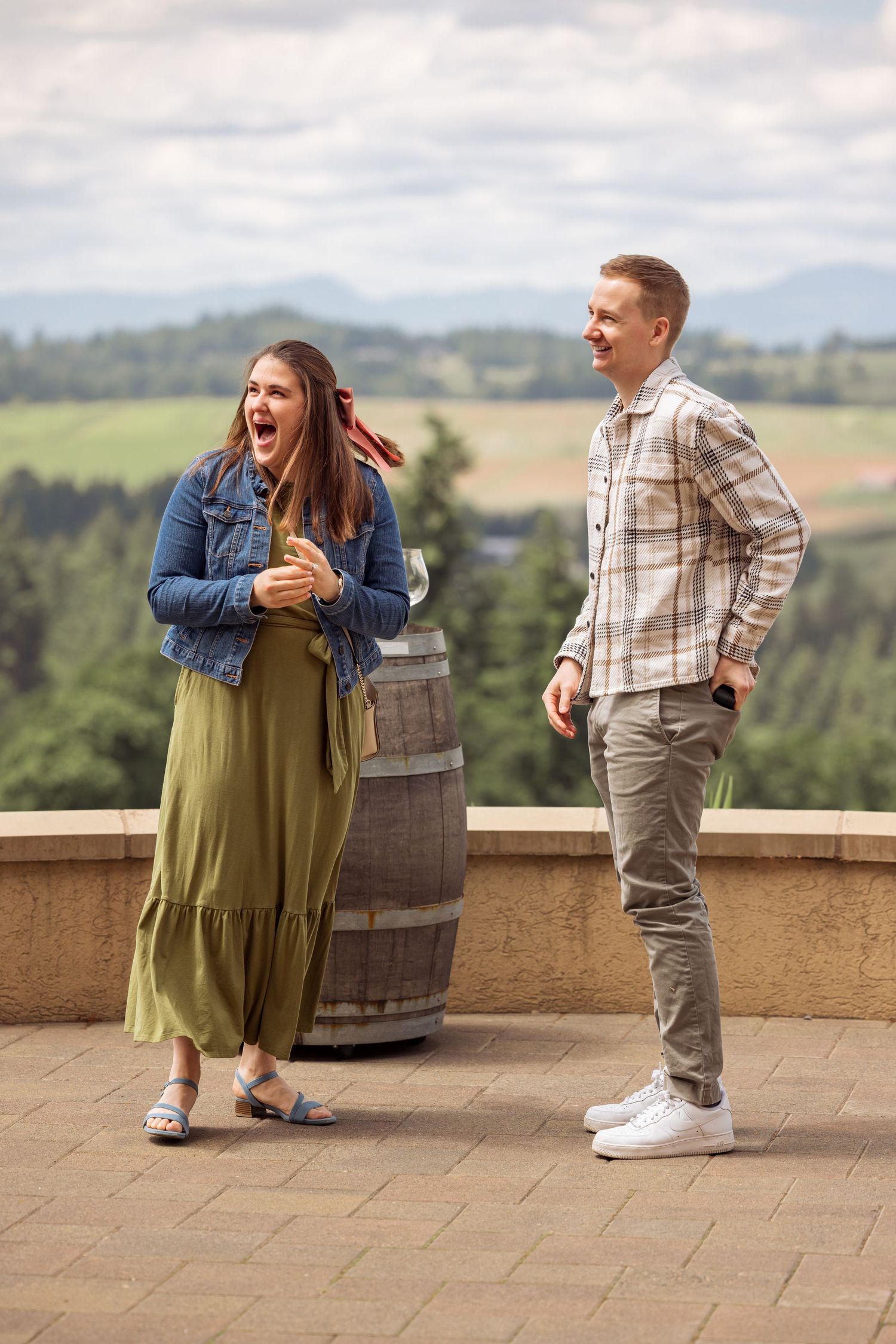 A surprised reaction during what appears to be a proposal moment at a scenic winery overlook.