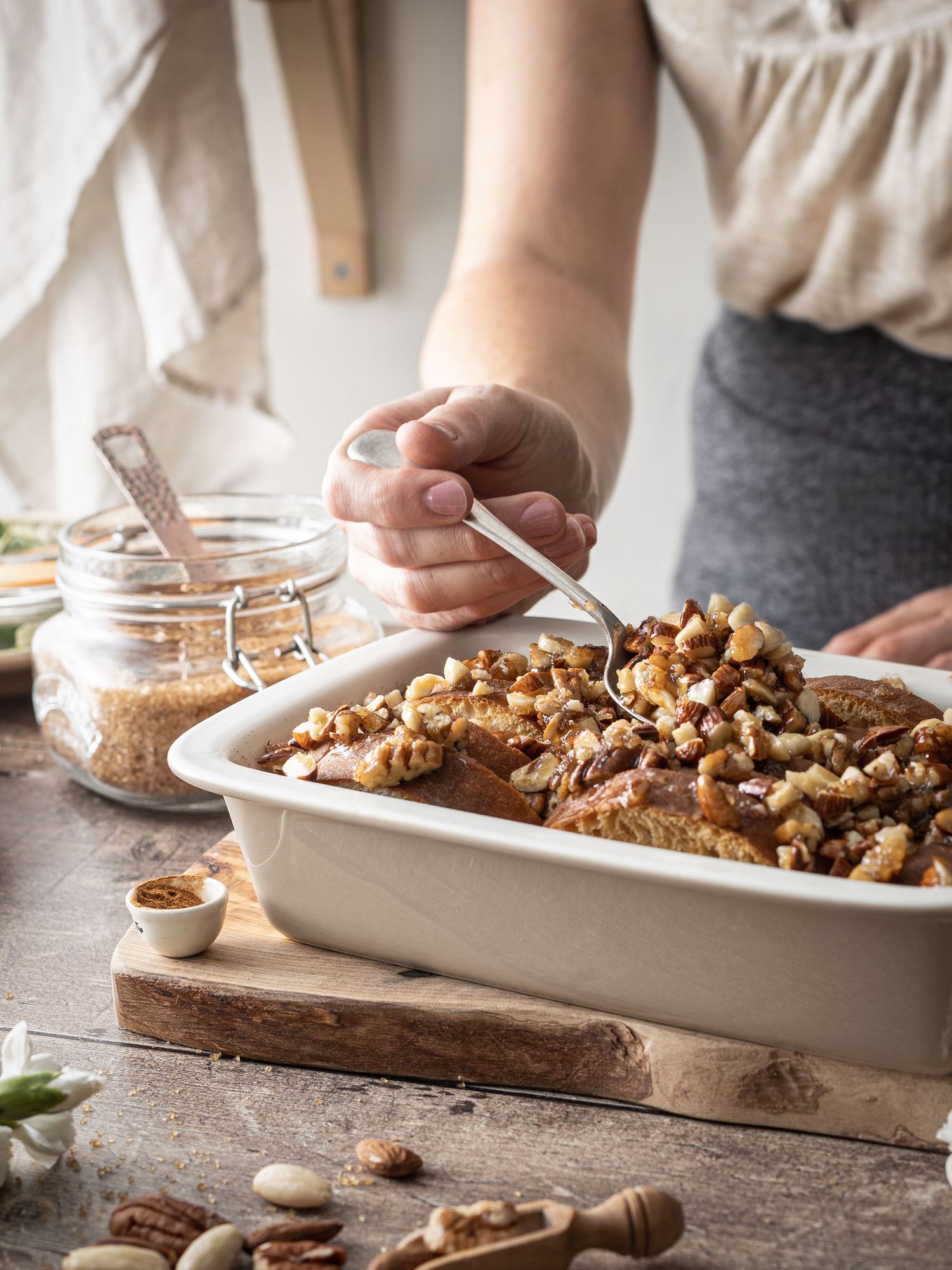 A woman stood behind a table serving homemade Baked French toast from baking dish