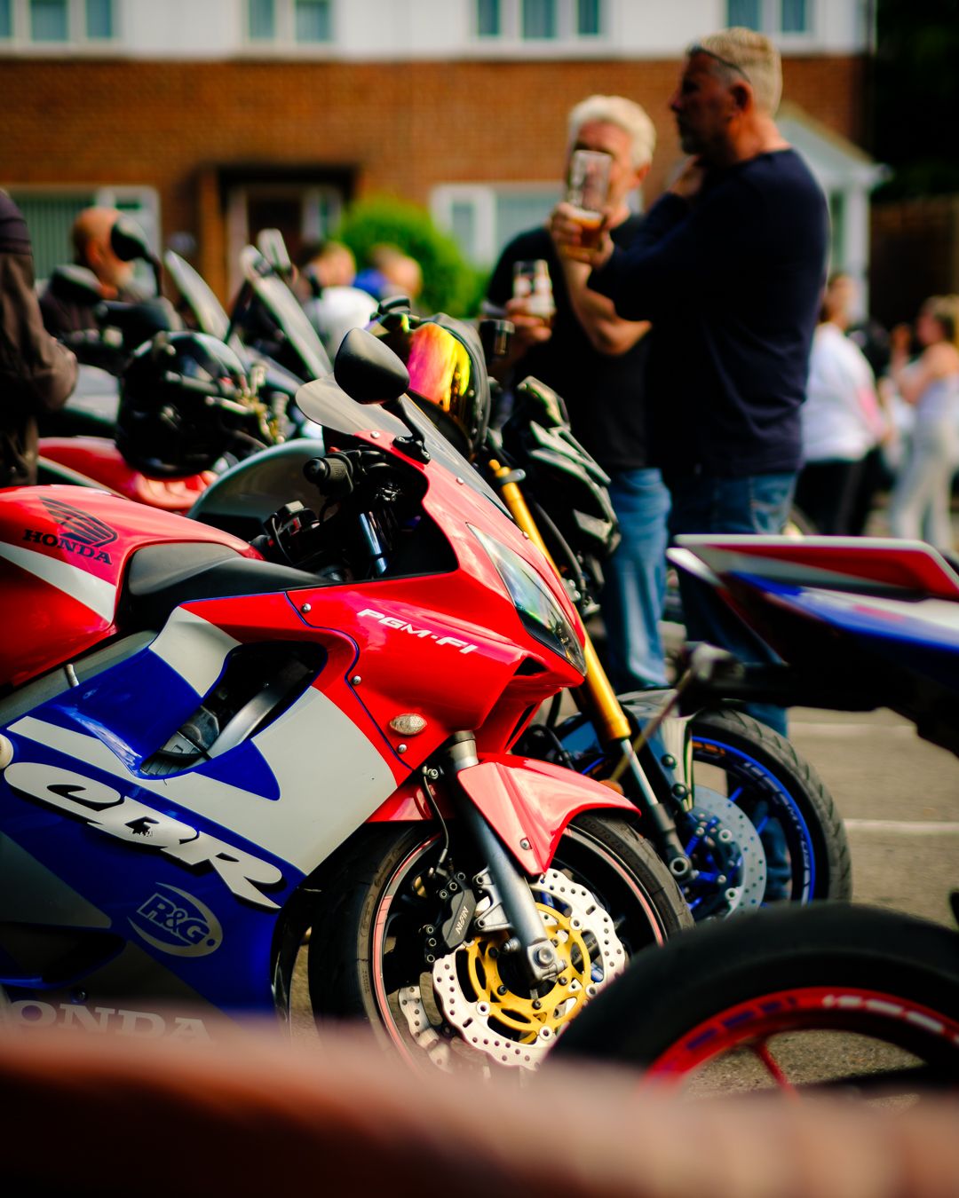 A row of colorful sport motorcycles including red and blue bikes lined up at an outdoor event.