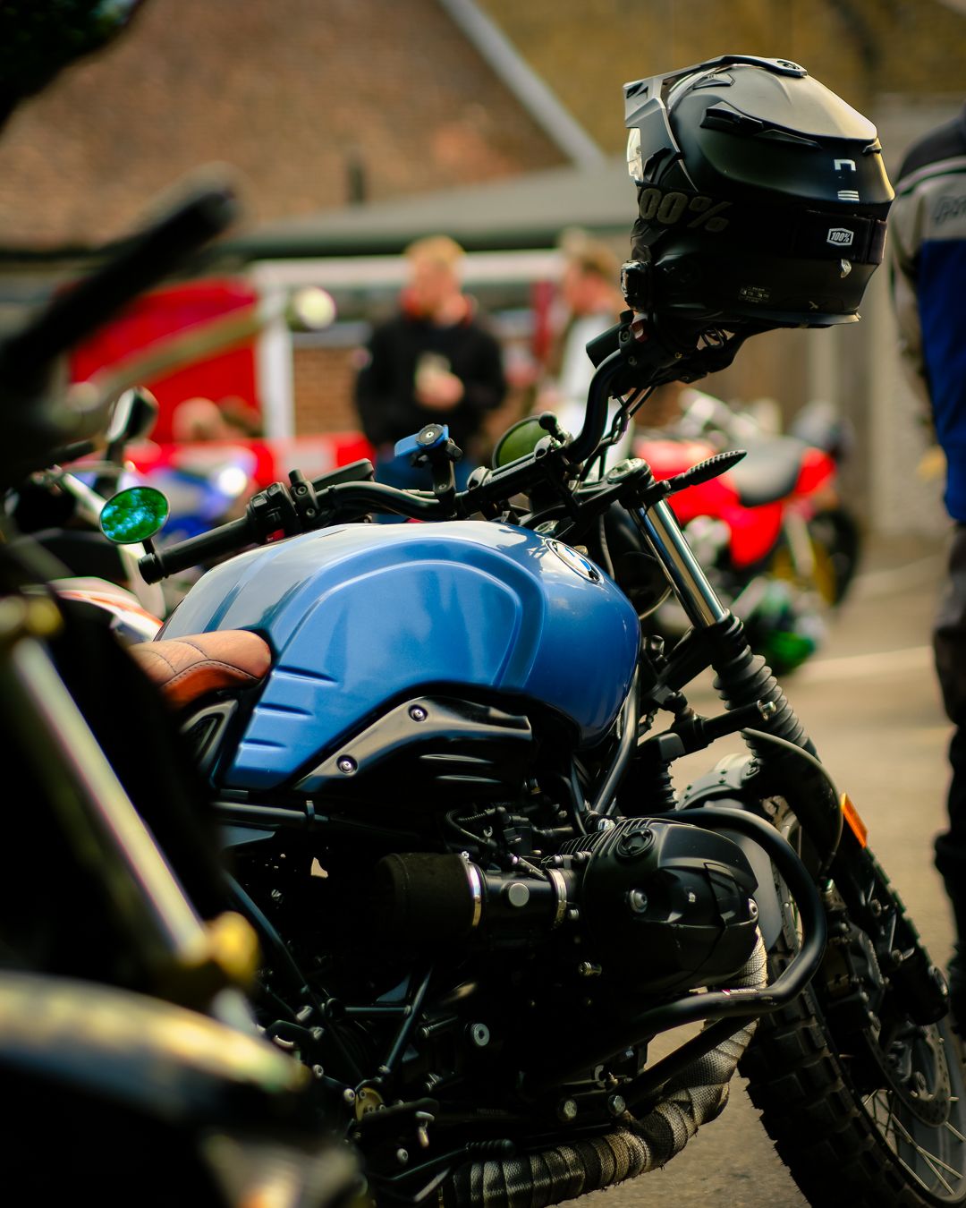 Close-up view of a blue motorcycle tank and handlebars on display at an outdoor event.