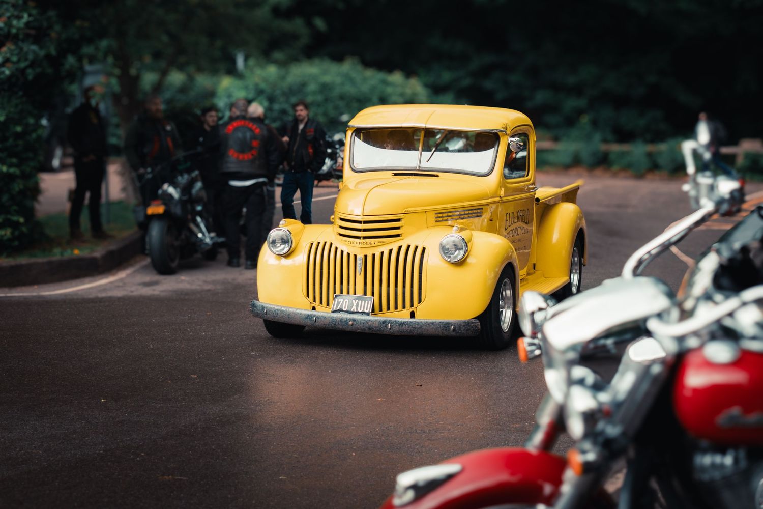 A collection of vintage yellow and red classic cars displayed in a park setting.