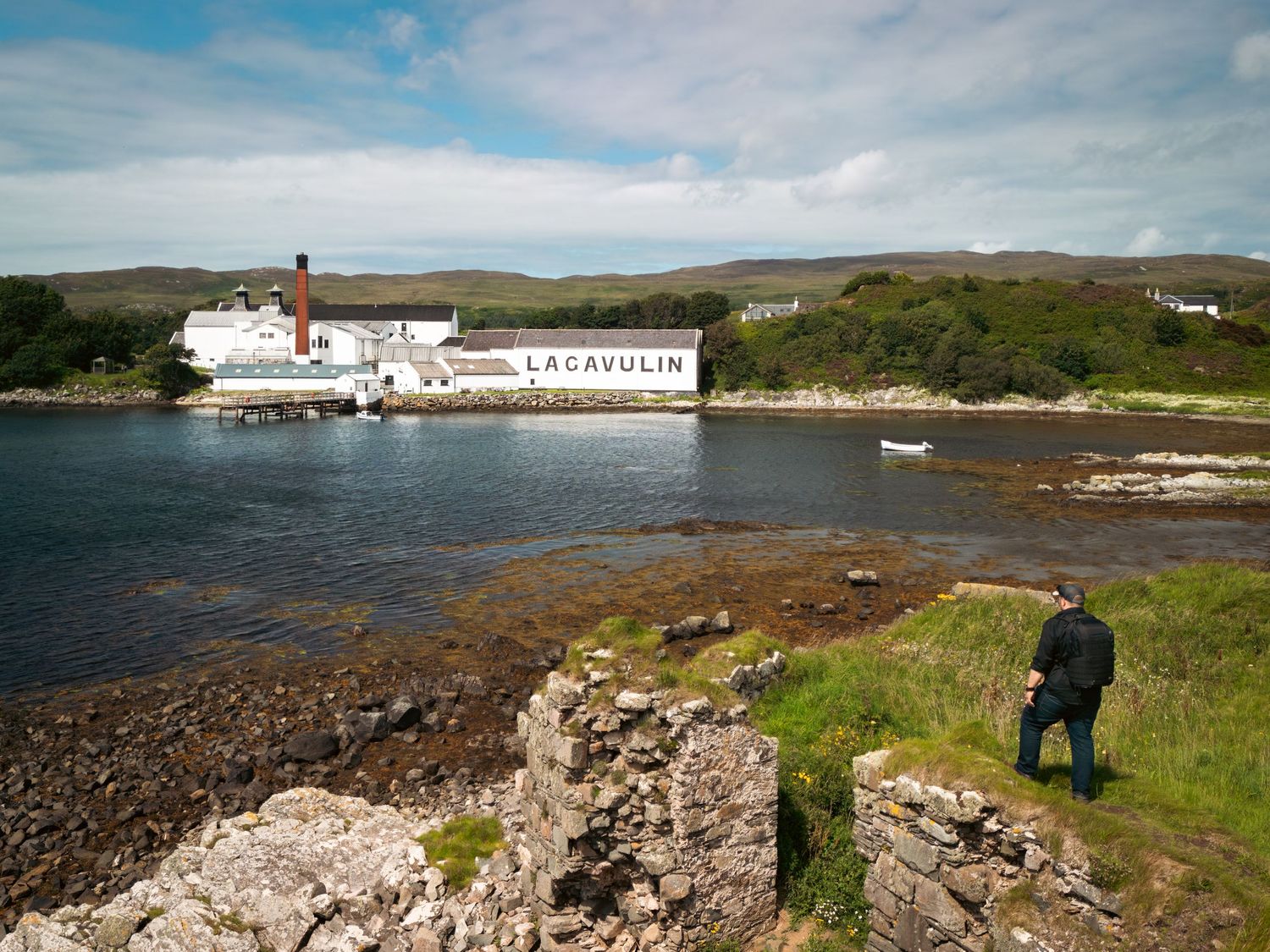 A panoramic view of the rugged Scottish coastal landscape with rocky shoreline and scattered white buildings.