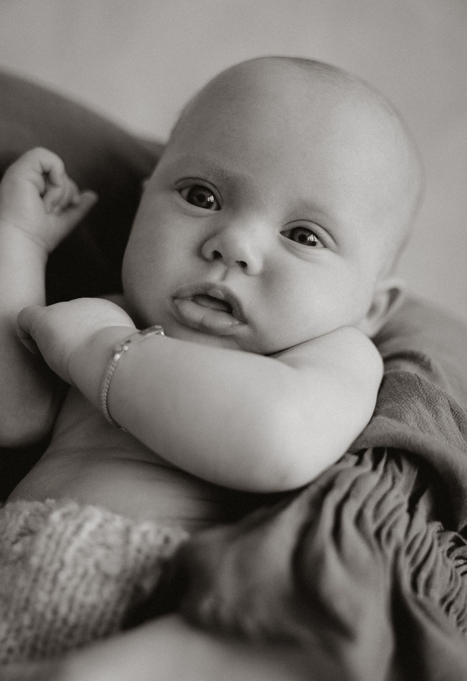 Pasgeboren baby ligt in handen en kijkt recht in de lens – Myrthegwen Fotografie Groningen