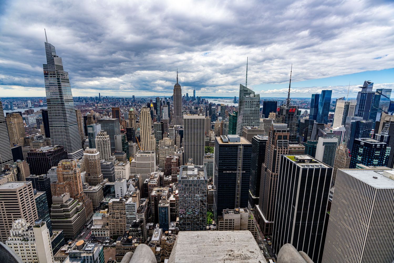Panoramic view of New York City skyline with modern skyscrapers under cloudy sky.