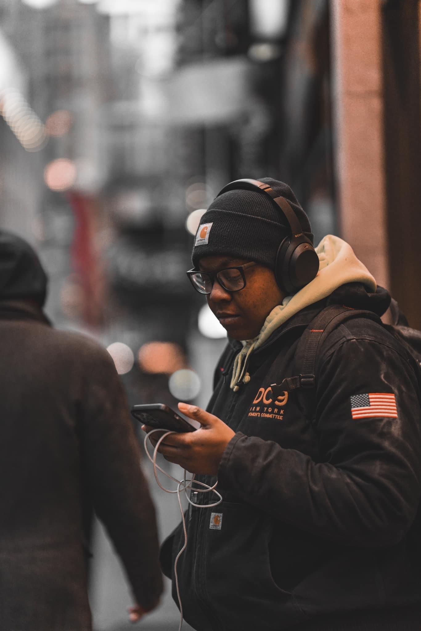 Urban street scene with person wearing black jacket and American flag patch.
