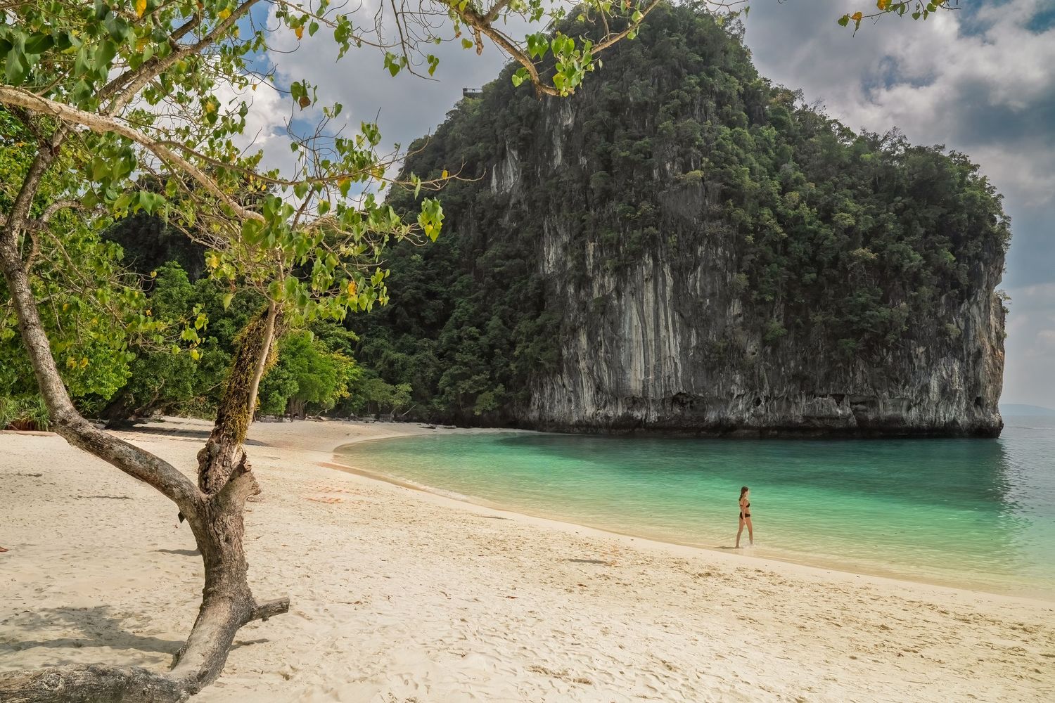 Pristine white sand beach with dramatic limestone cliffs and crystal clear turquoise waters.