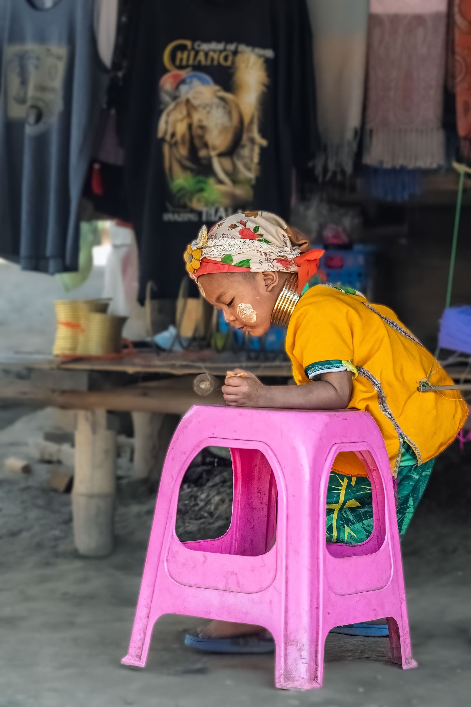 Small child playing on a pink plastic table in a casual outdoor setting.