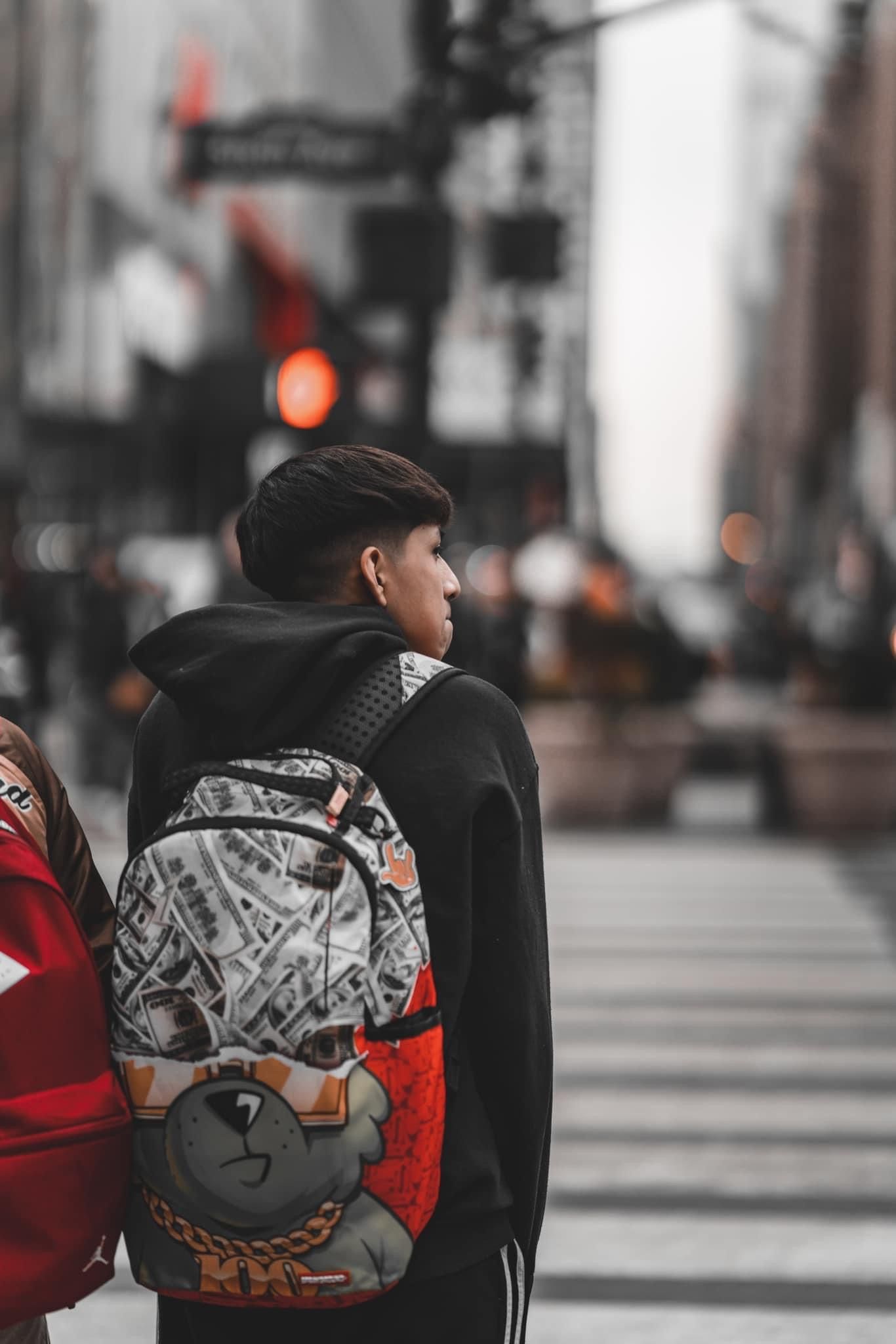 Person wearing backpack with geometric patterns walking on city street.