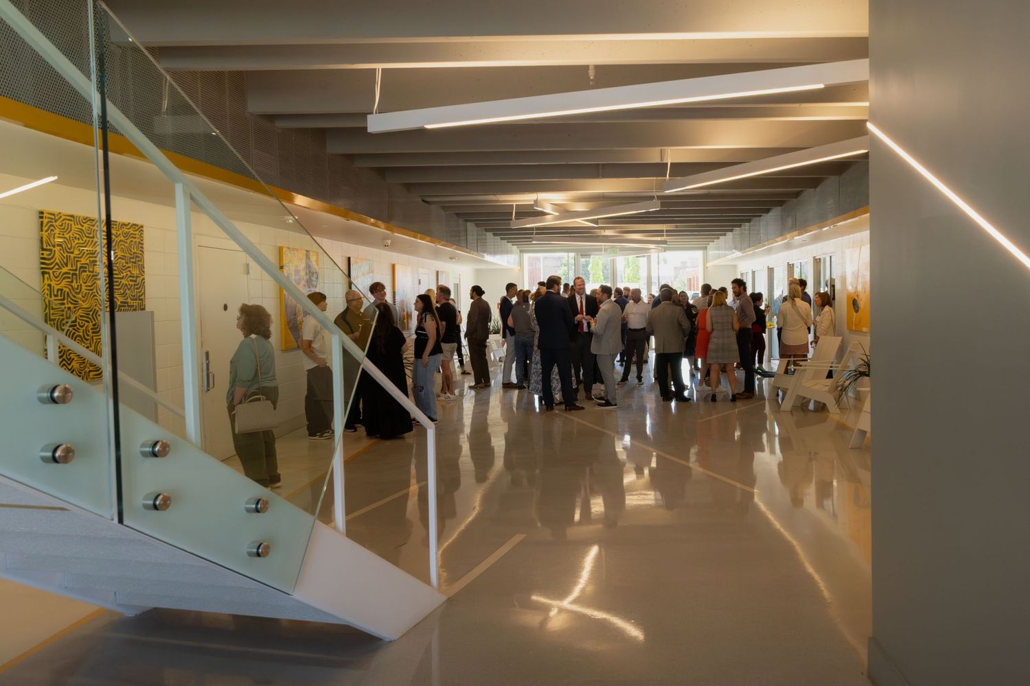 Contemporary office corridor with glass walls and modern lighting fixtures.