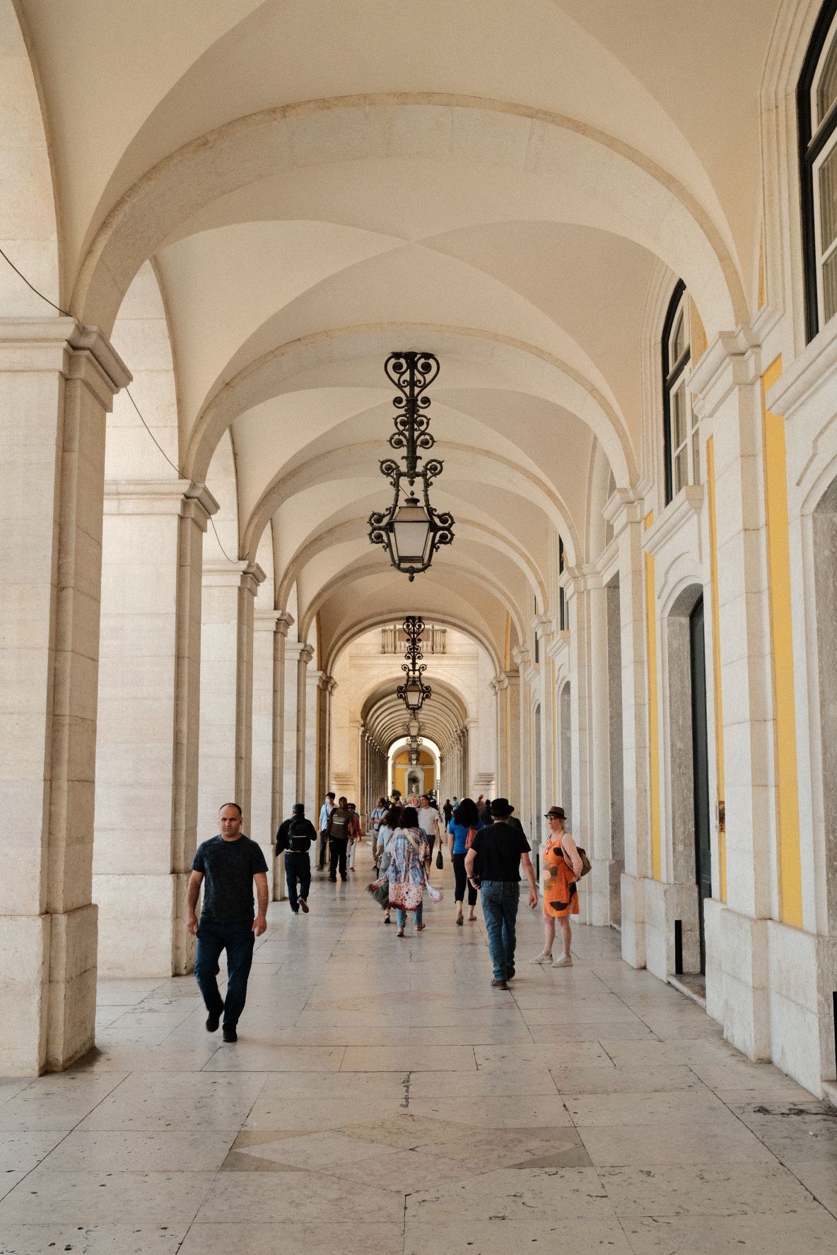 Elegant arched colonnade hallway with vaulted ceilings and hanging lanterns.