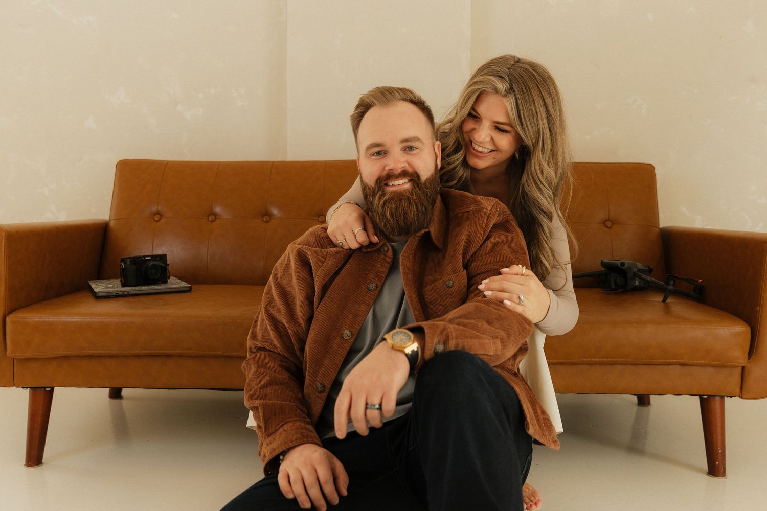 Couple relaxing together on a brown leather couch in a cozy living room setting.