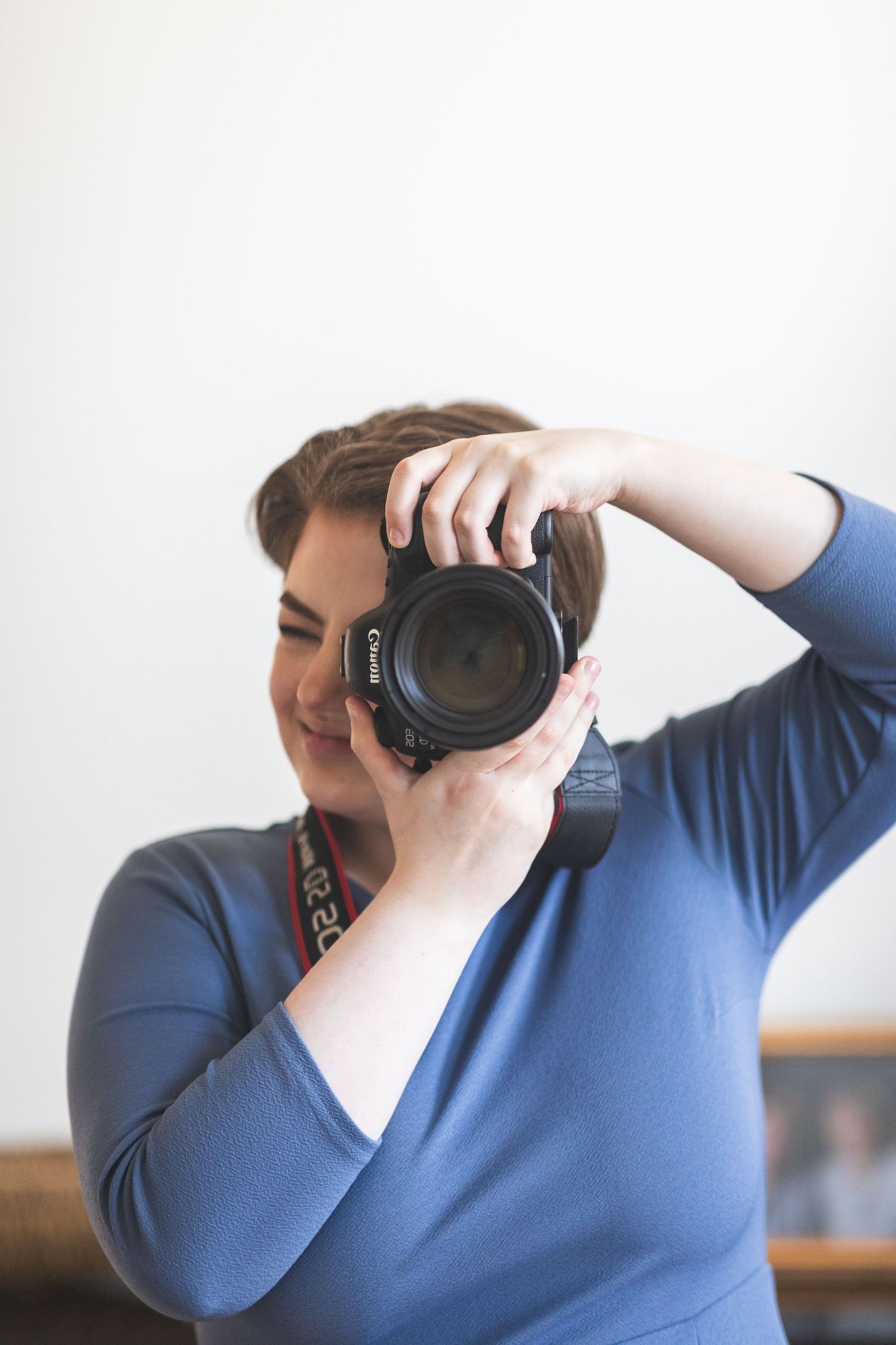 Photographer takes her own photo in a mirror, wearing a blue dress.