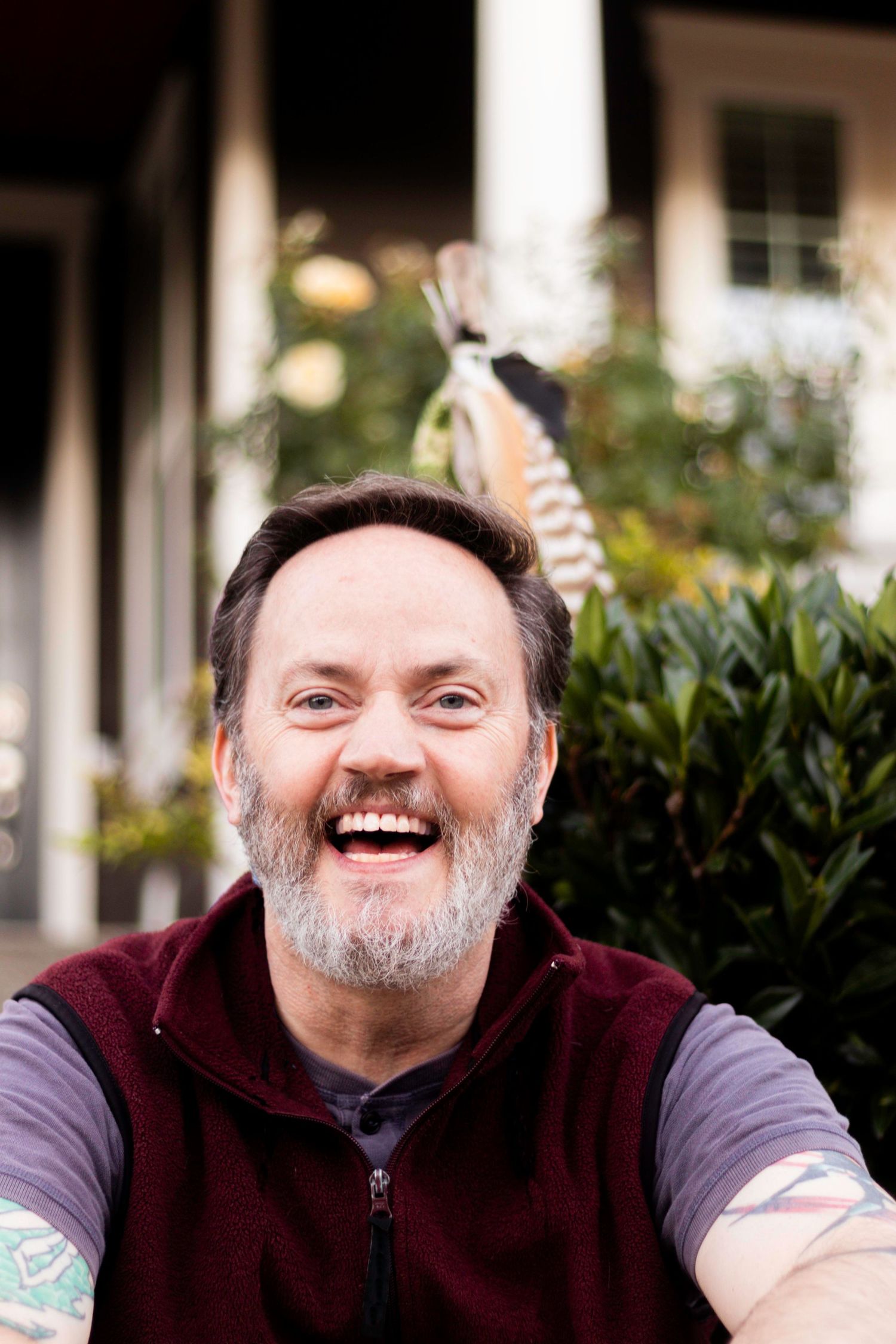 50-something man with a gray beard laughs, smiling wide for the camera.