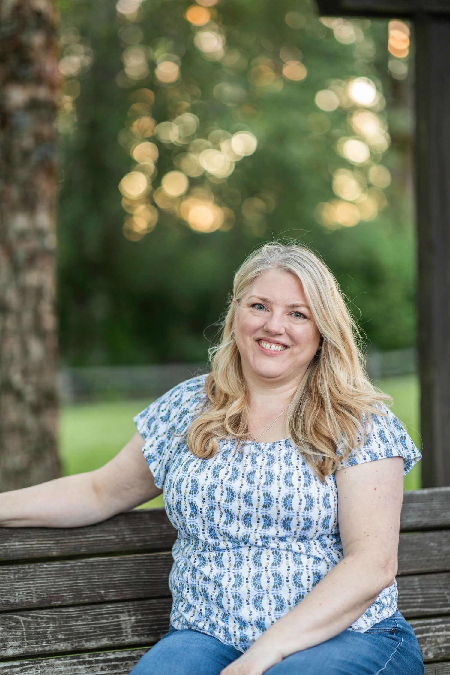 A mother smiles for the camera, wearing a blue patterned shirt.