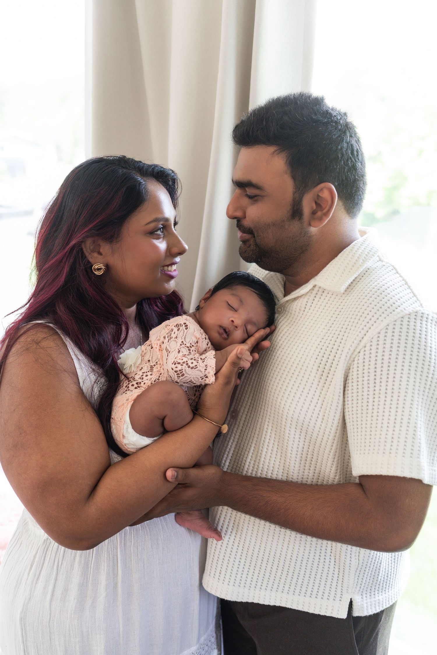 New parents gaze at each other while holding their new baby.