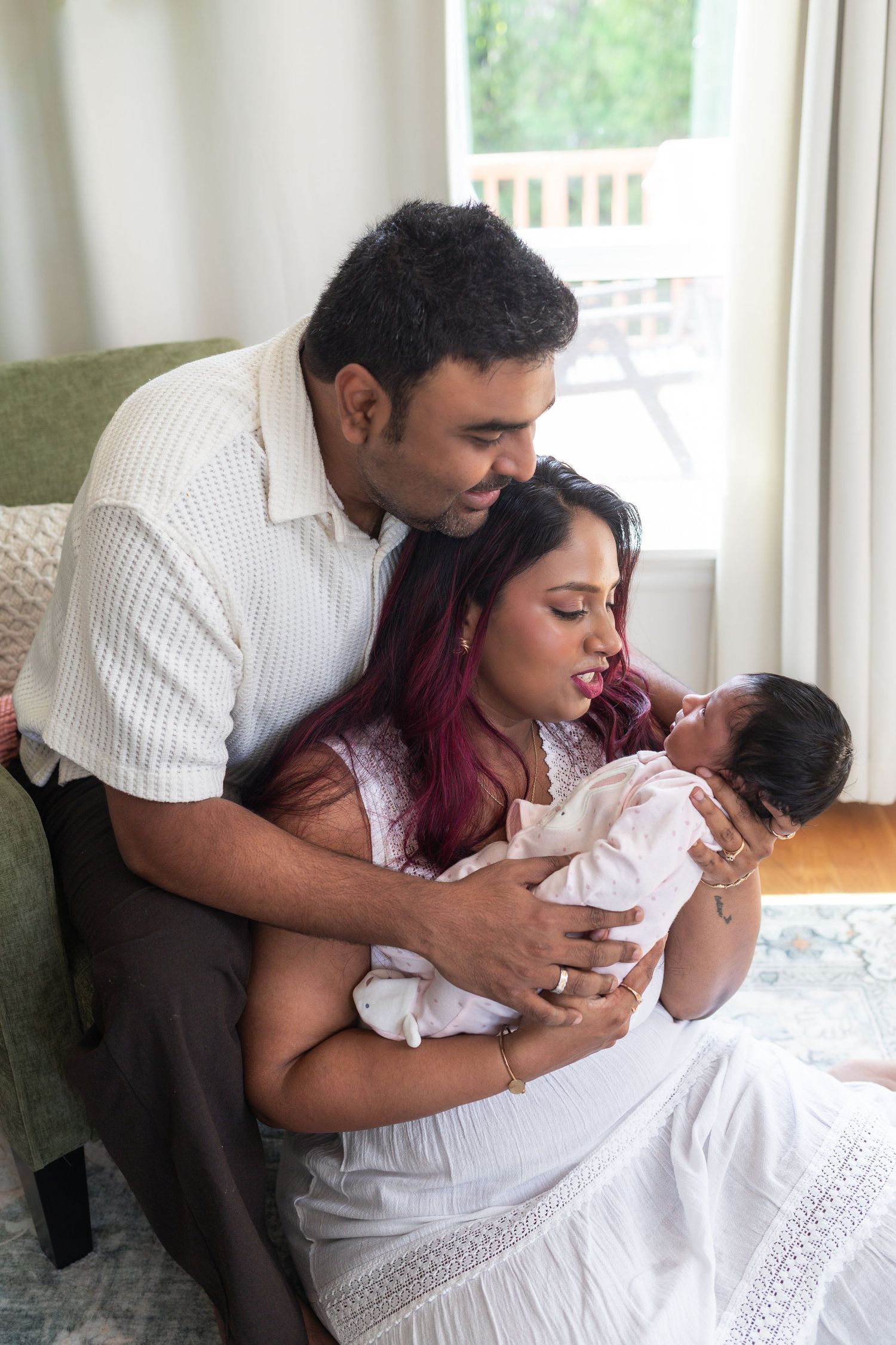 Newborn baby held by her mother while mom and dad look at her happily.