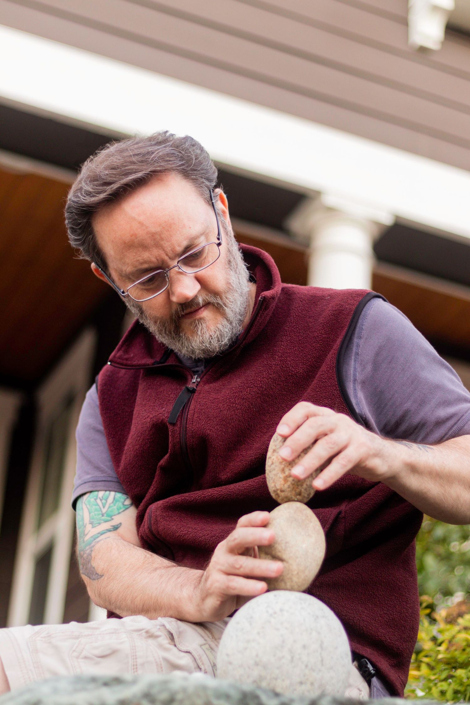 50-something man with a gray beard stacks rocks.