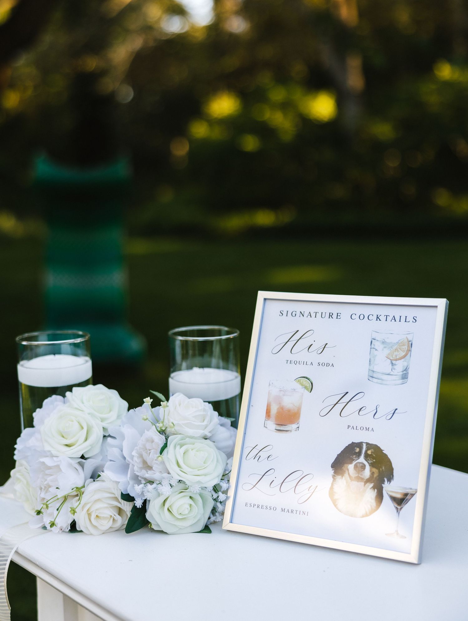 Wedding reception drink menu and white roses displayed on an elegant table setting.