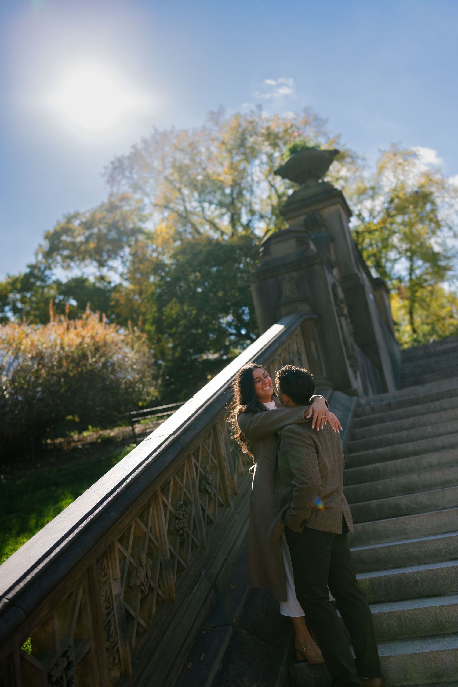A couple shares romantic moments on stone steps in a park during autumn.