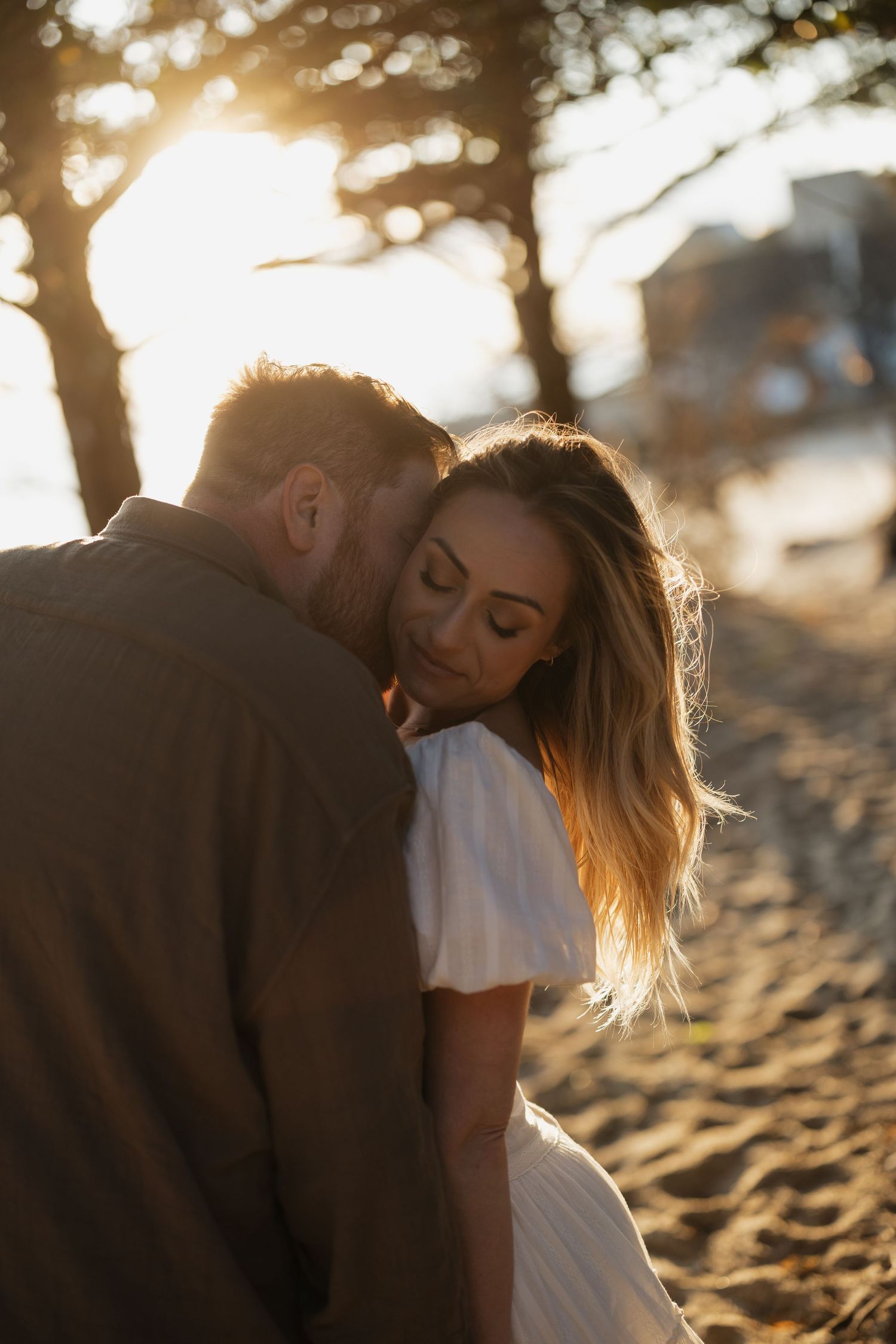 Romantic couple sharing intimate moments on a sandy beach during golden hour sunset.