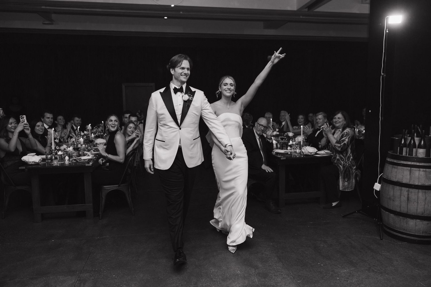 Newlyweds make a grand entrance at their reception, dancing together in black and white.