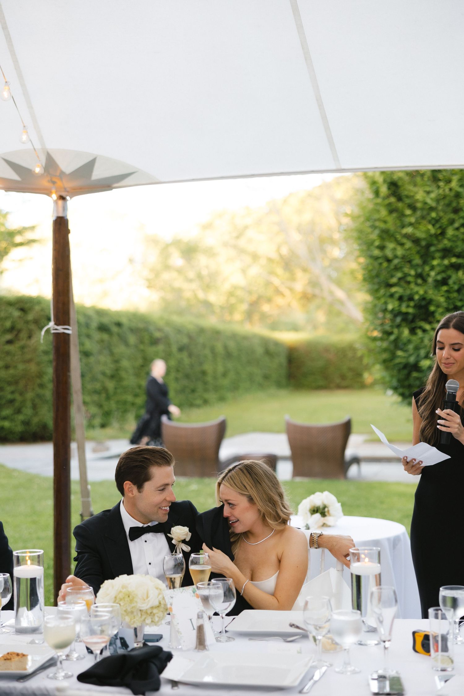 Wedding reception dining setup under white tent with mountain views in background.