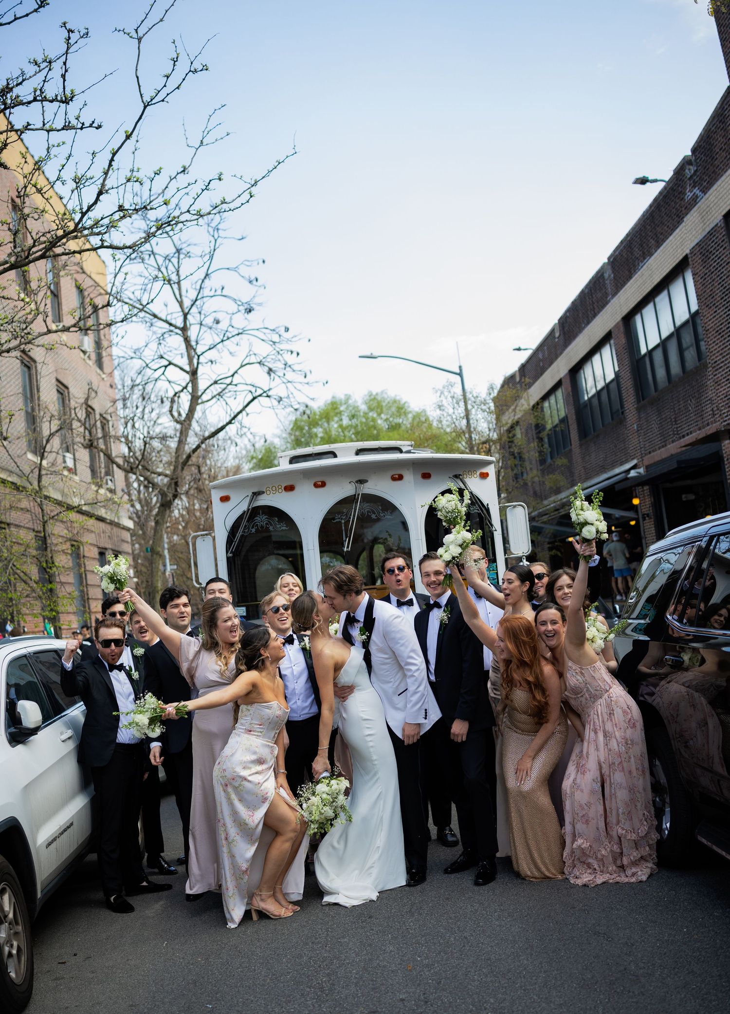 Wedding party celebrates outside with a decorated vintage car.