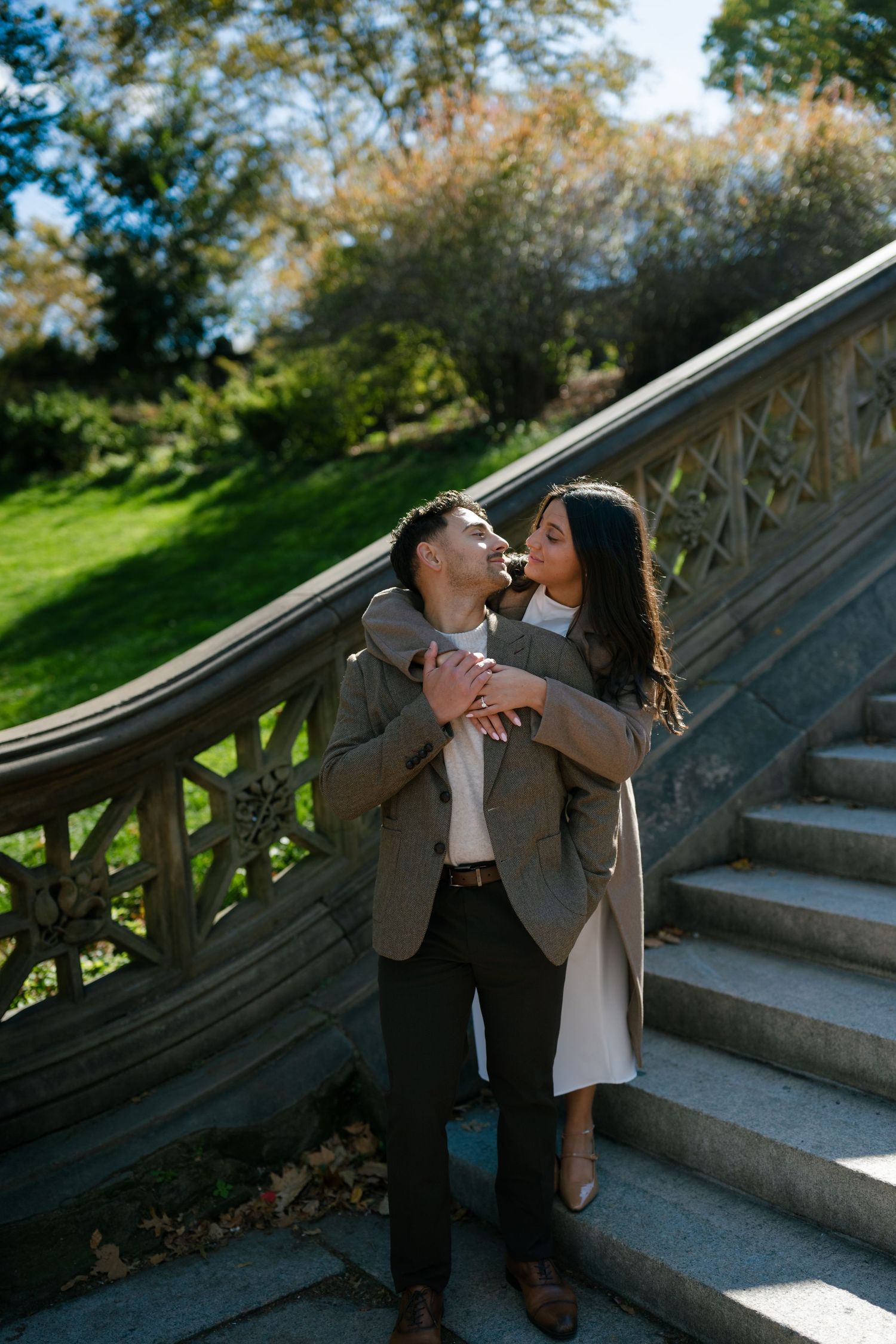 Two people share playful and intimate moments on outdoor stone steps in natural lighting.