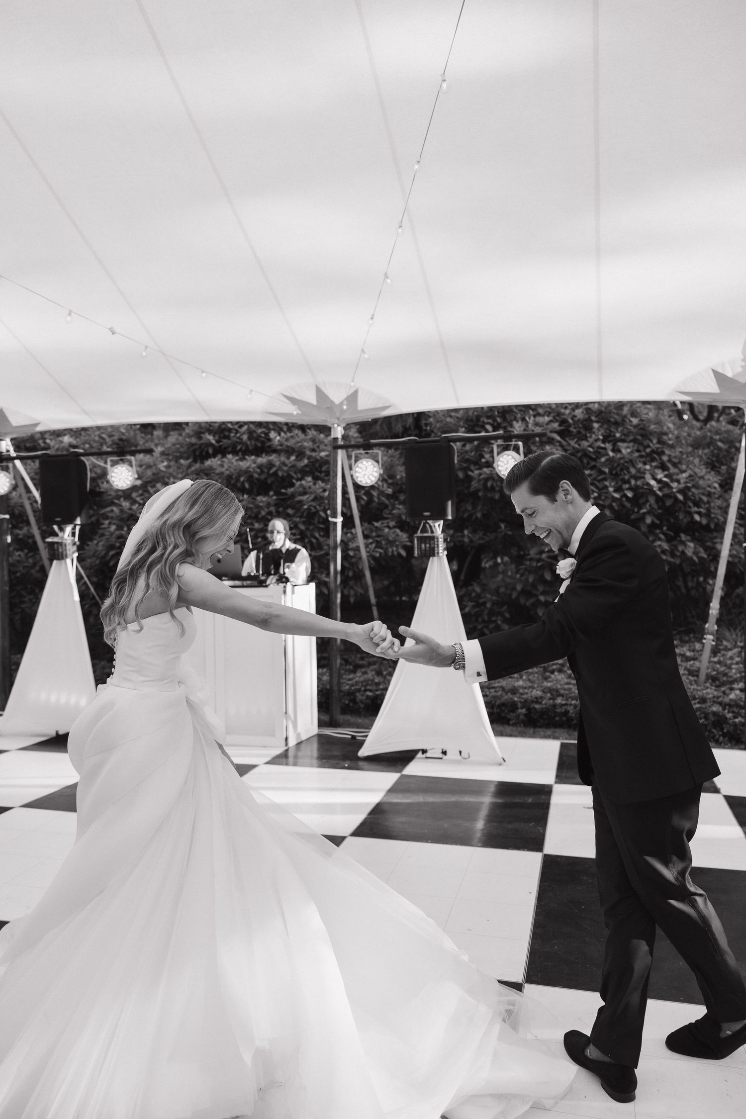 Black and white photos of a wedding couple dancing under a white tent at an outdoor reception.