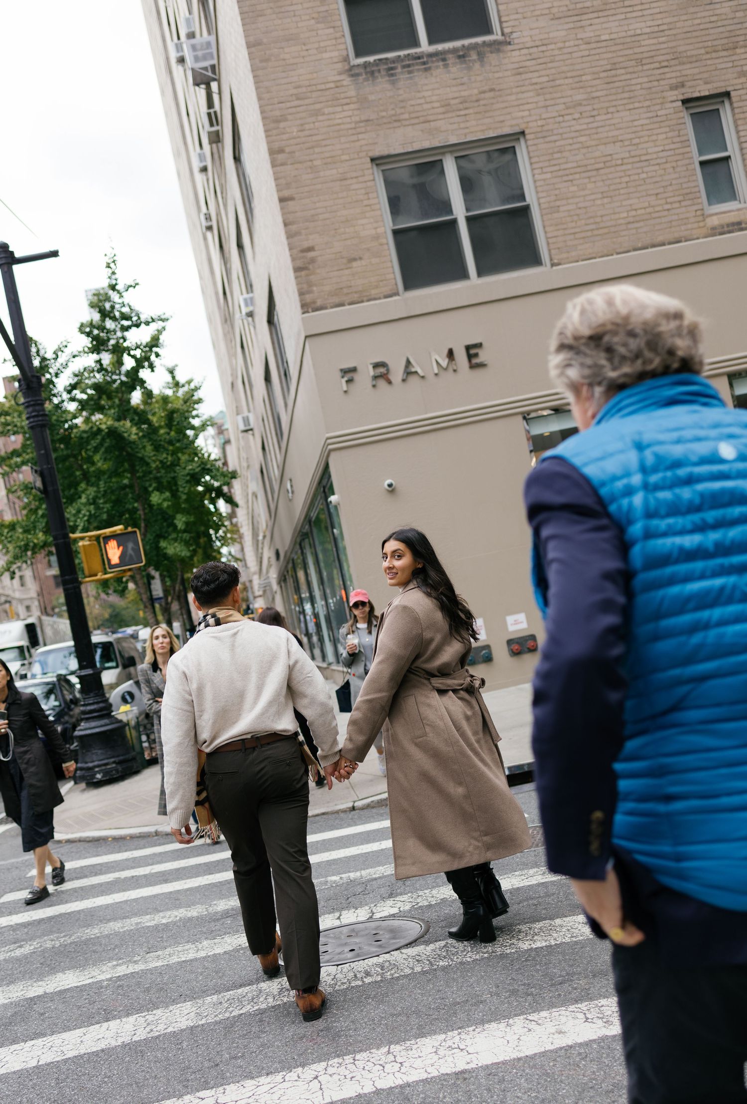 People crossing an urban intersection with brick buildings and blue sky in the background.